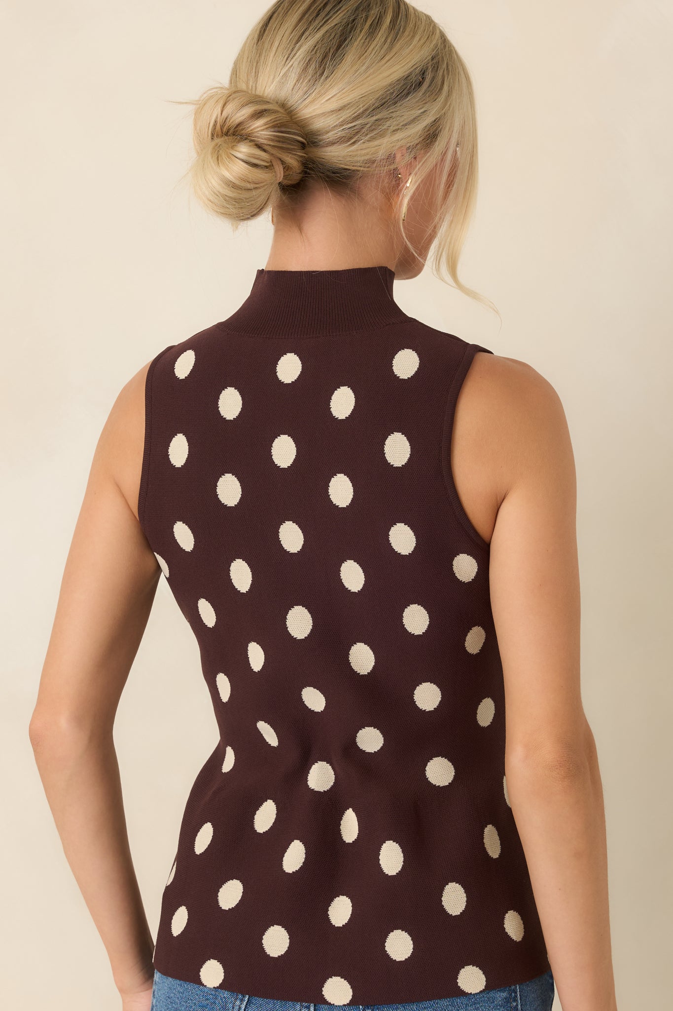 Rear view of the chocolate brown sweater knit top showcasing the sleeveless design, fitted shape, and peplum hem.