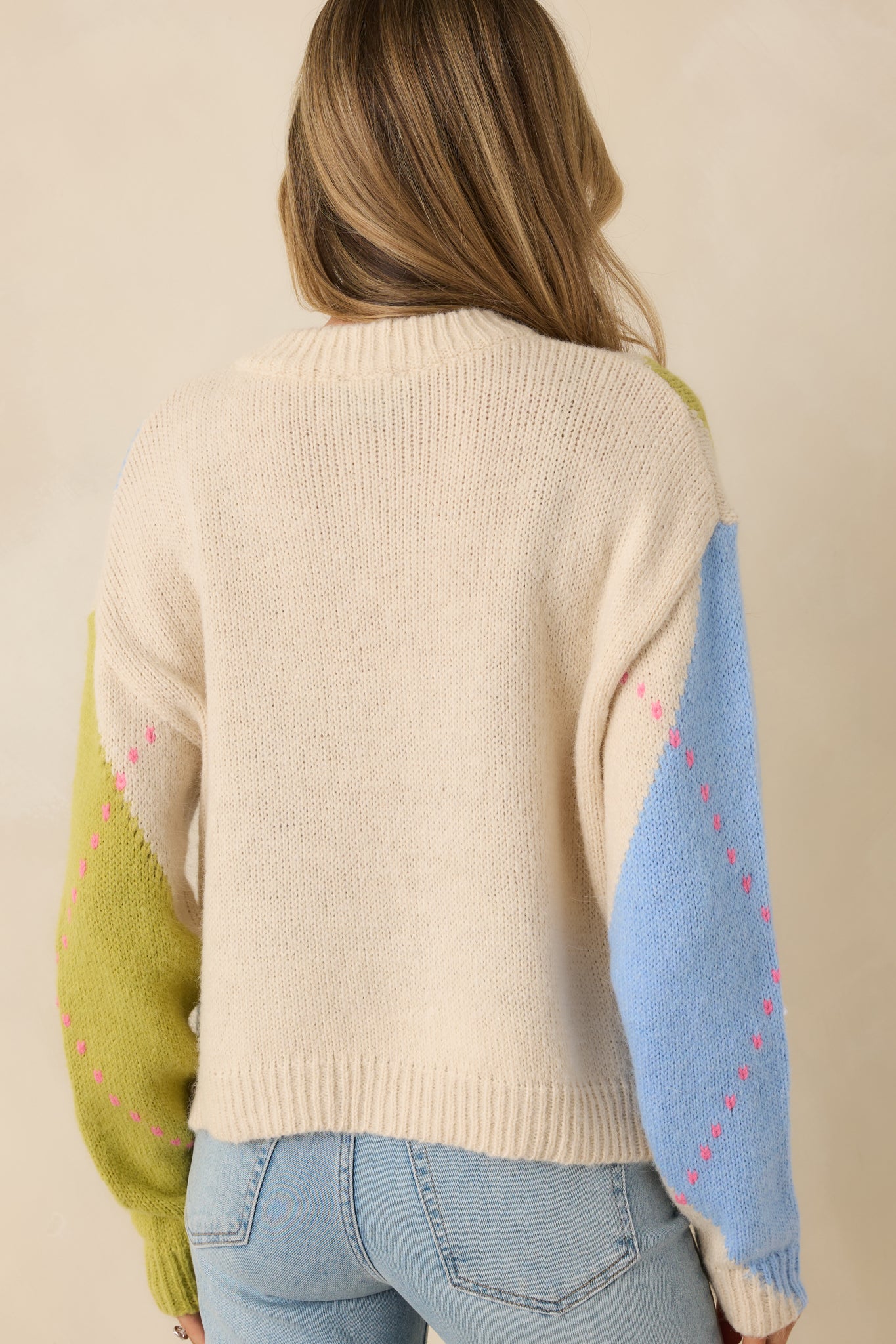 Rear view of green and blue argyle knit sweater with continuous diamond pattern and ribbed hem.