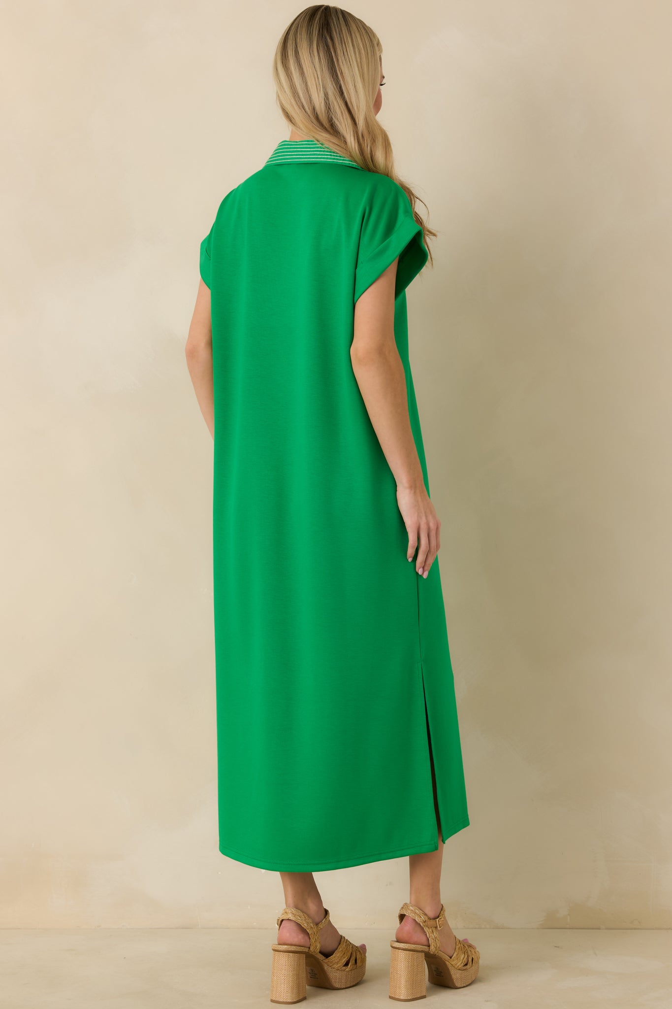 Rear view of green knit midi dress with straight silhouette and clean hemline.