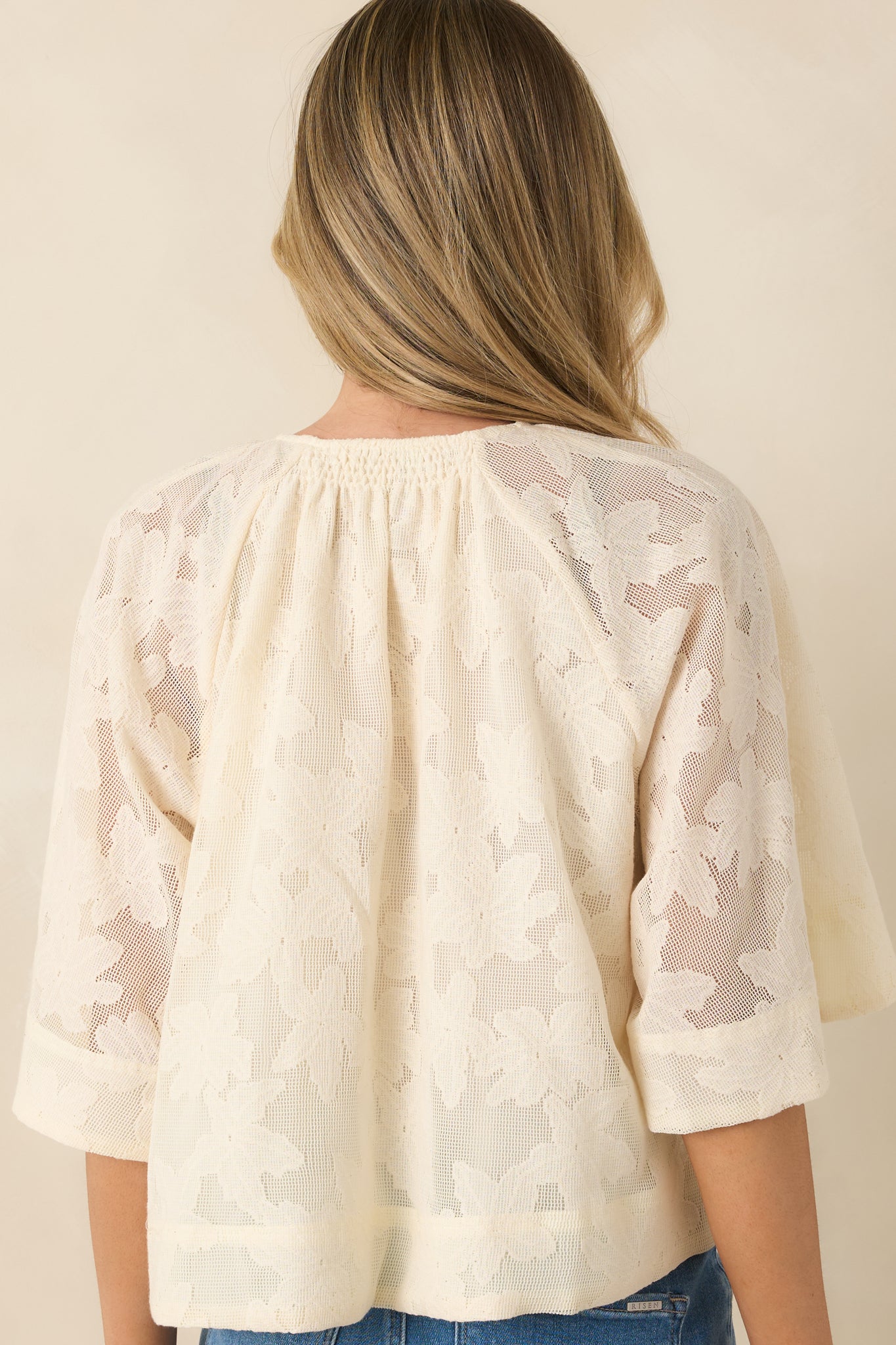 Rear view of ivory blouse with eyelet embroidery and three-quarter kimono sleeves.