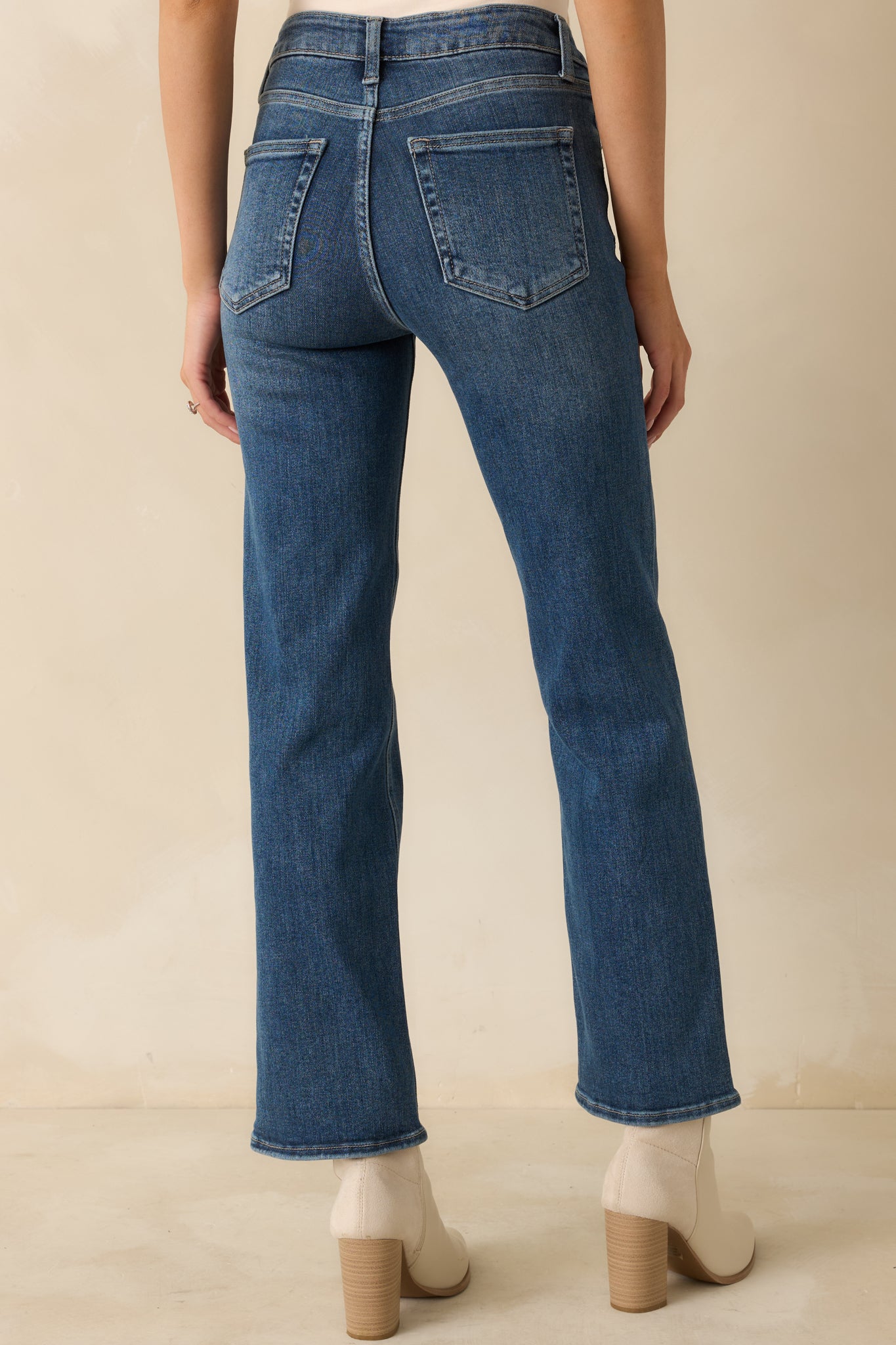 Rear view of medium wash straight-leg jeans showing classic back pockets, high-rise fit, and subtle color variation.