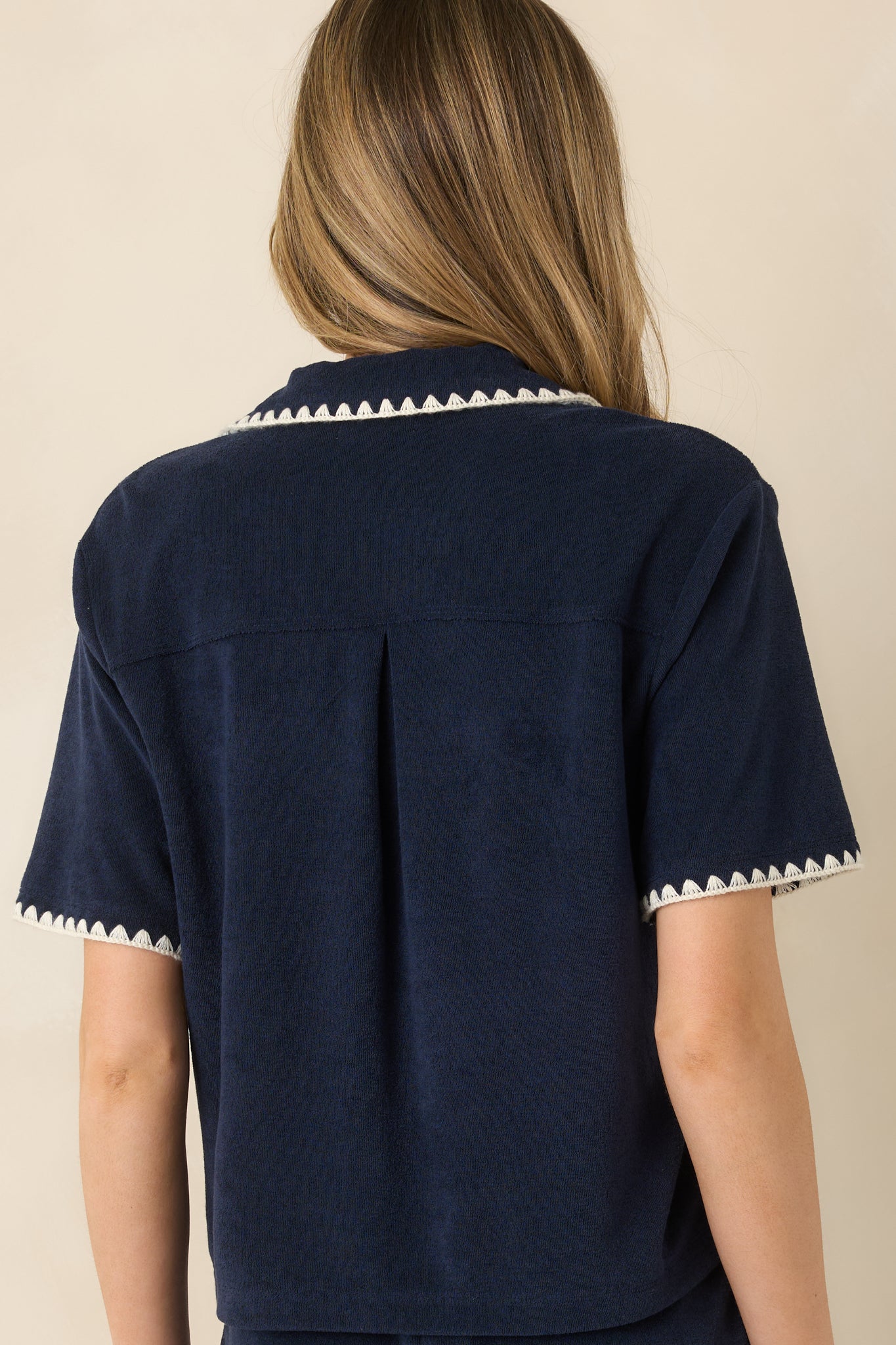 Rear view of navy short-sleeve button-down top with collared neckline and relaxed fit.
