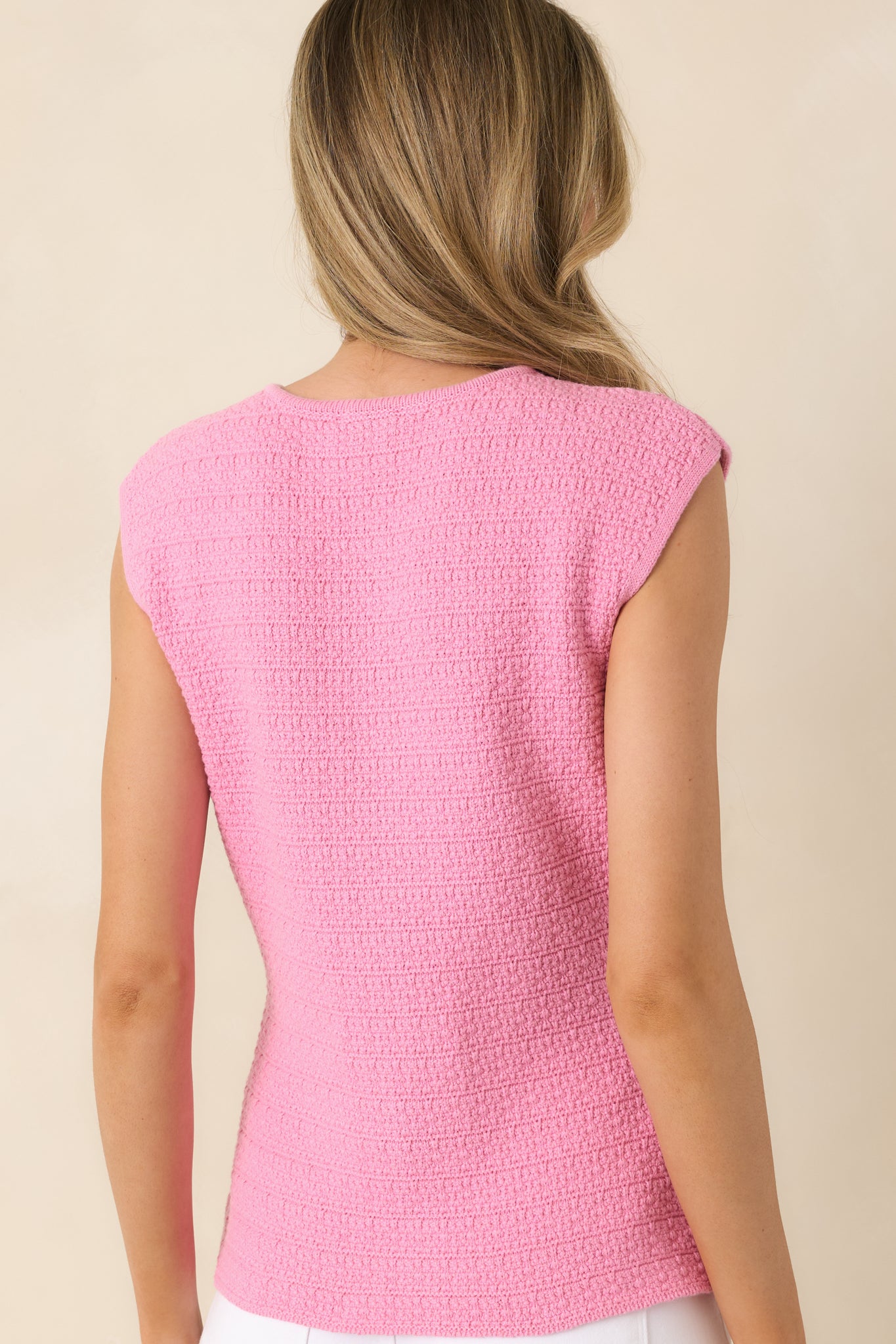 Rear view of pink textured sleeveless top with structured silhouette