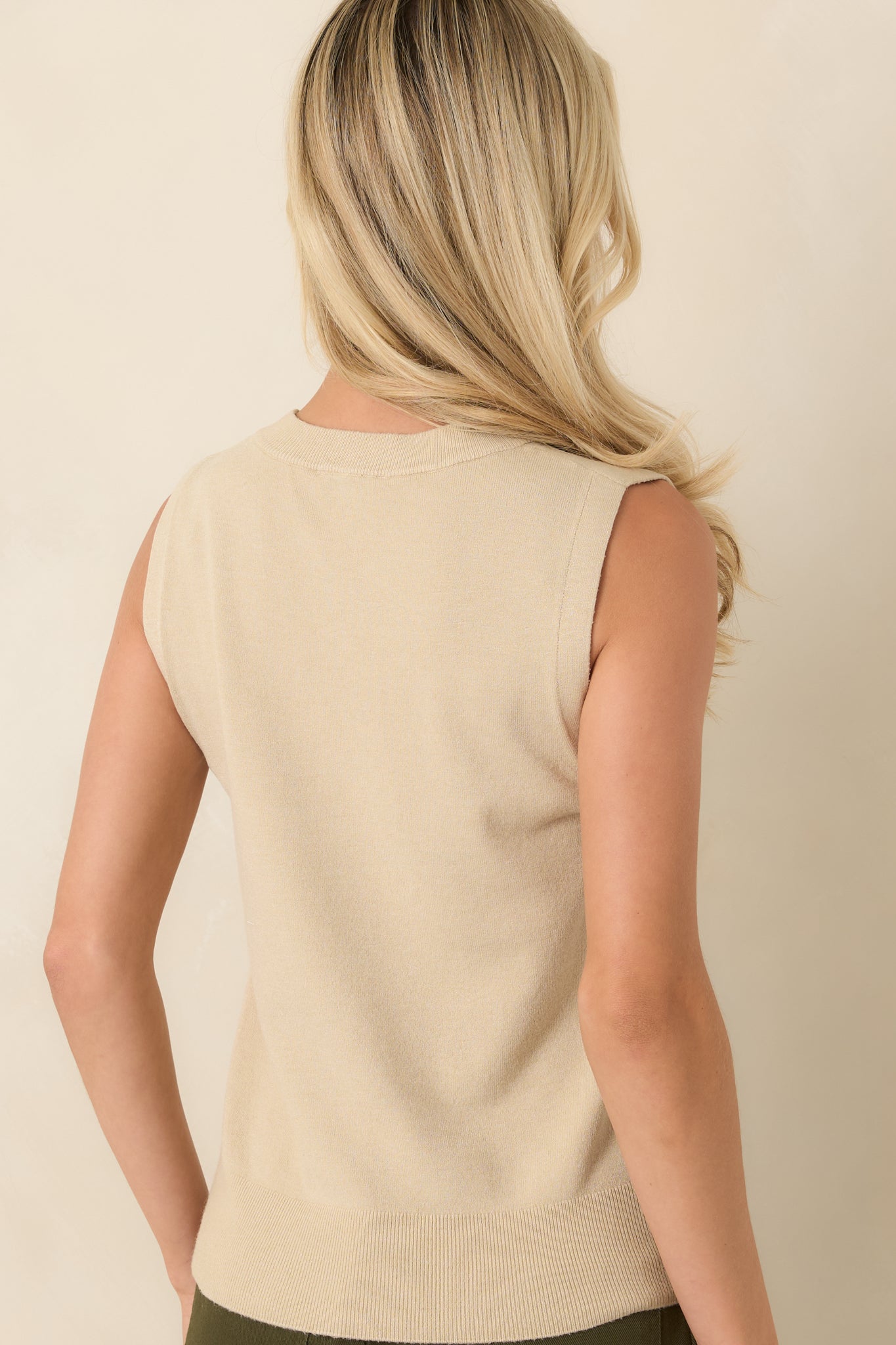 Rear view of the sleeveless knit sweater showcasing the smooth, uninterrupted design and ribbed hemline.