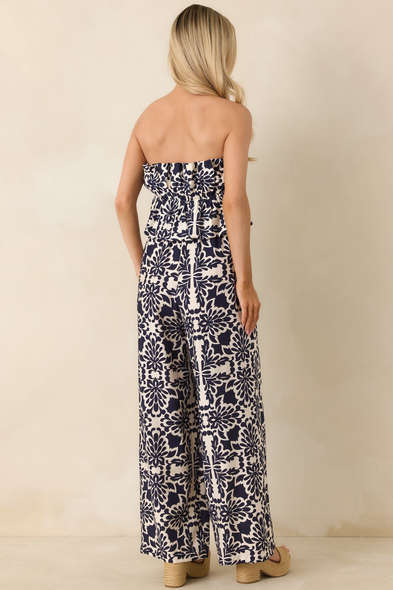 Rear view of strapless jumpsuit showing elastic back and flowing wide-leg silhouette.