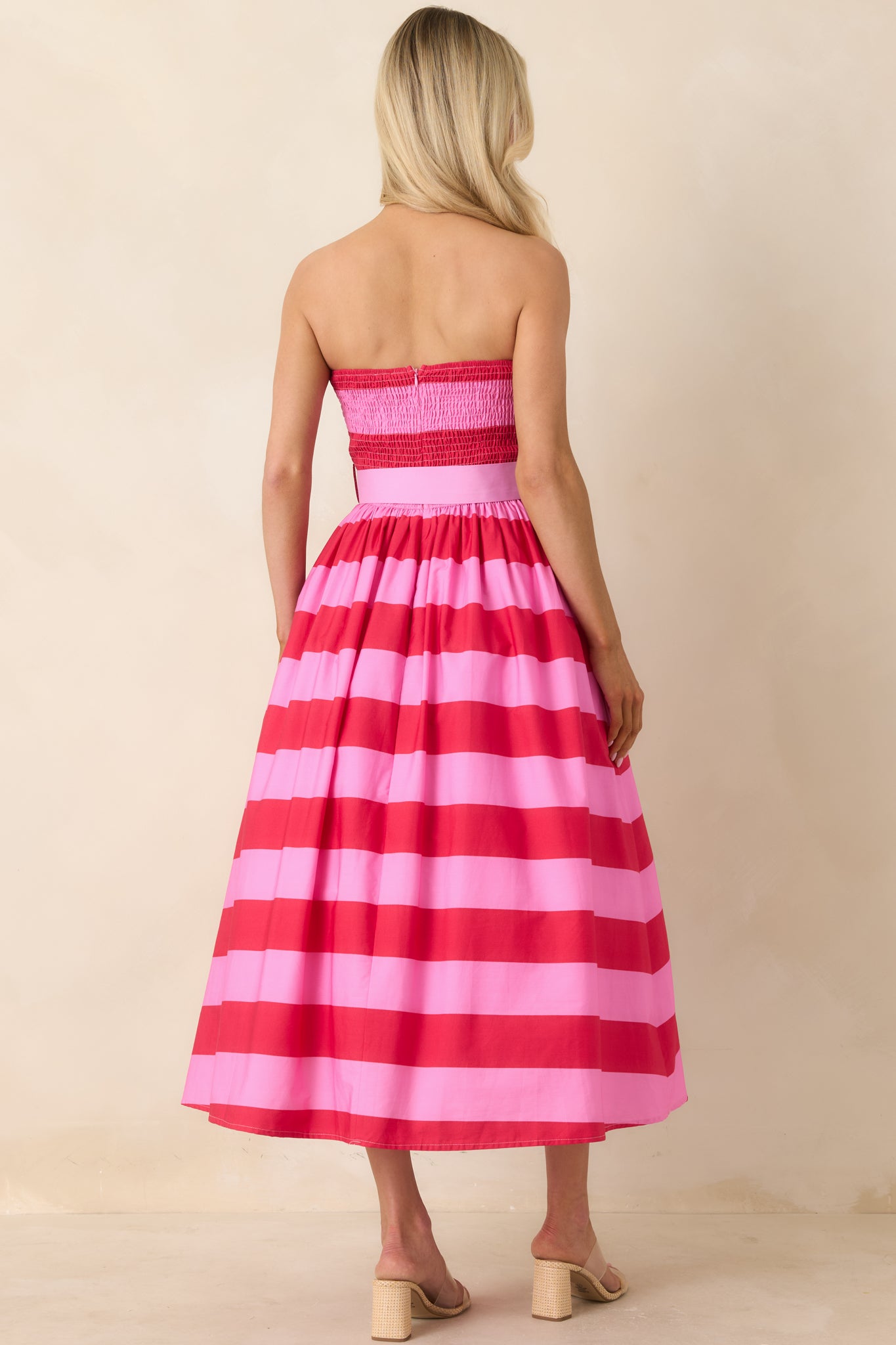 Rear view of strapless striped midi dress with structured bodice and flowing skirt.