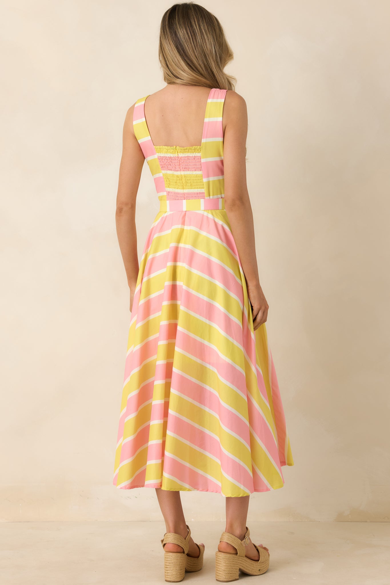 Rear view of striped midi dress with smocked back panel and flowing skirt.