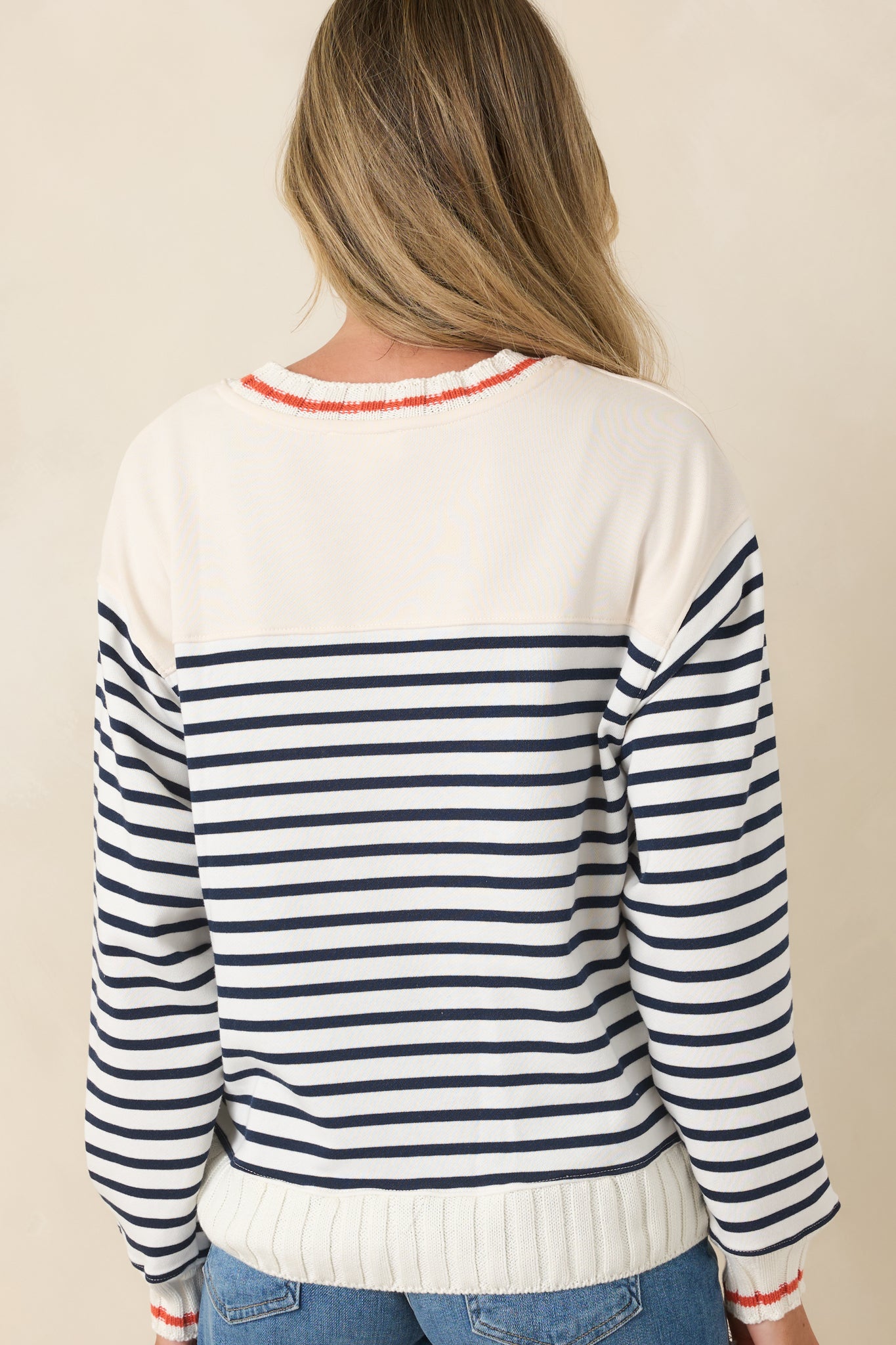 Rear view of the striped pullover showcasing the ivory base, long sleeves, and ribbed hem.