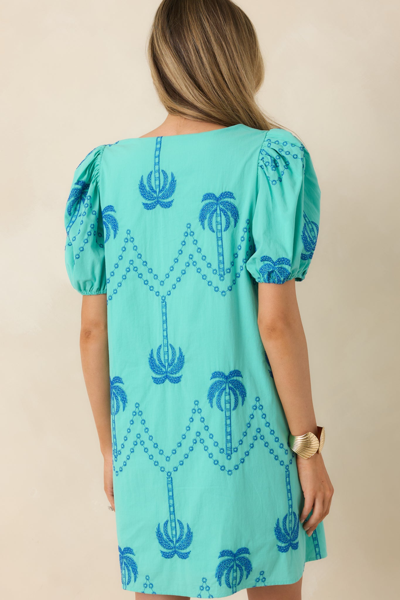 Rear view of teal mini dress with puff sleeves and clean lined silhouette.