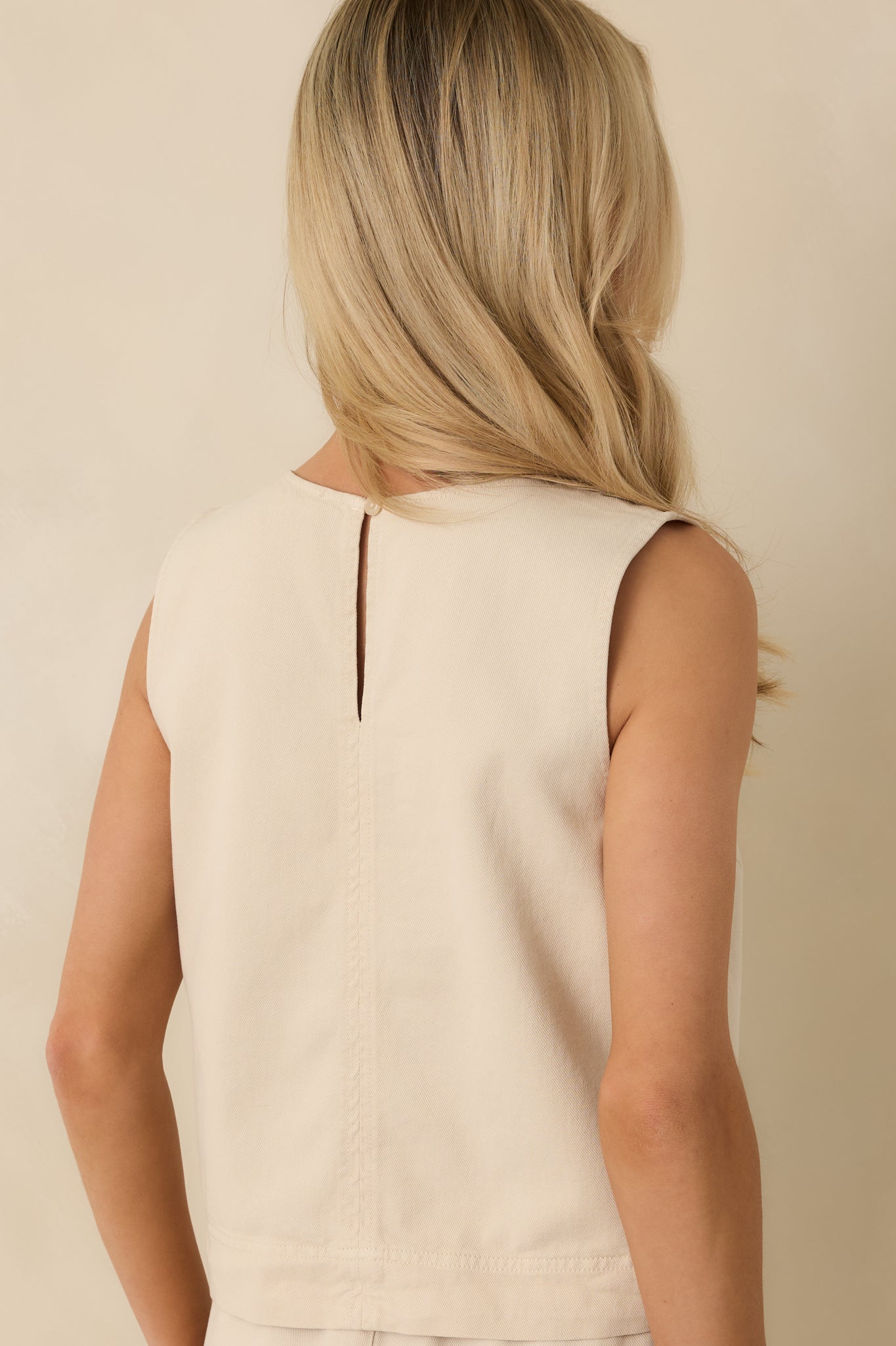 Rear view of the beige tank showing the subtle keyhole button closure and boxy fit.