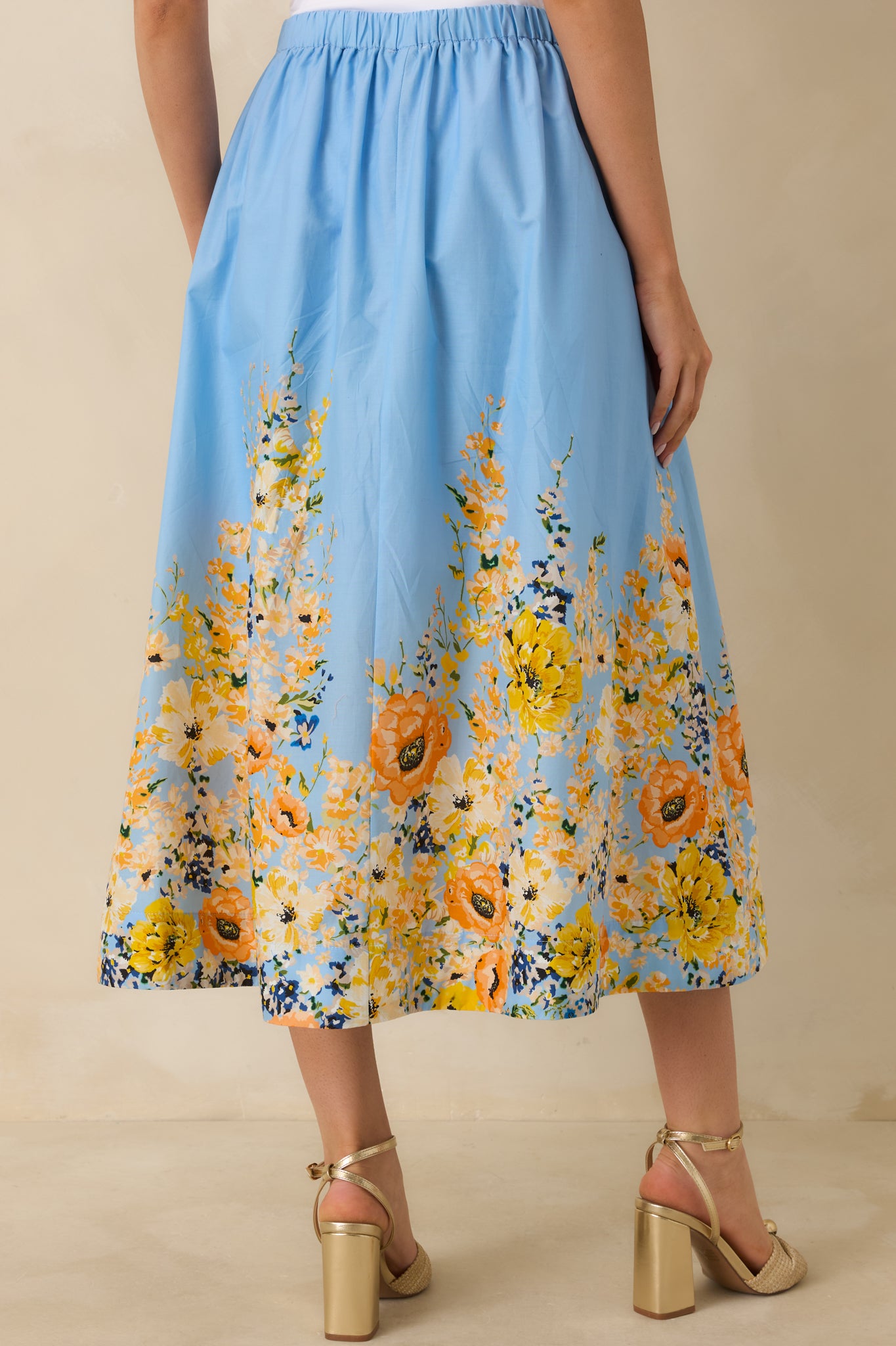 Rear view of the blue cotton maxi skirt showing the flowy silhouette, elastic waistband, and continuous floral hem print.
