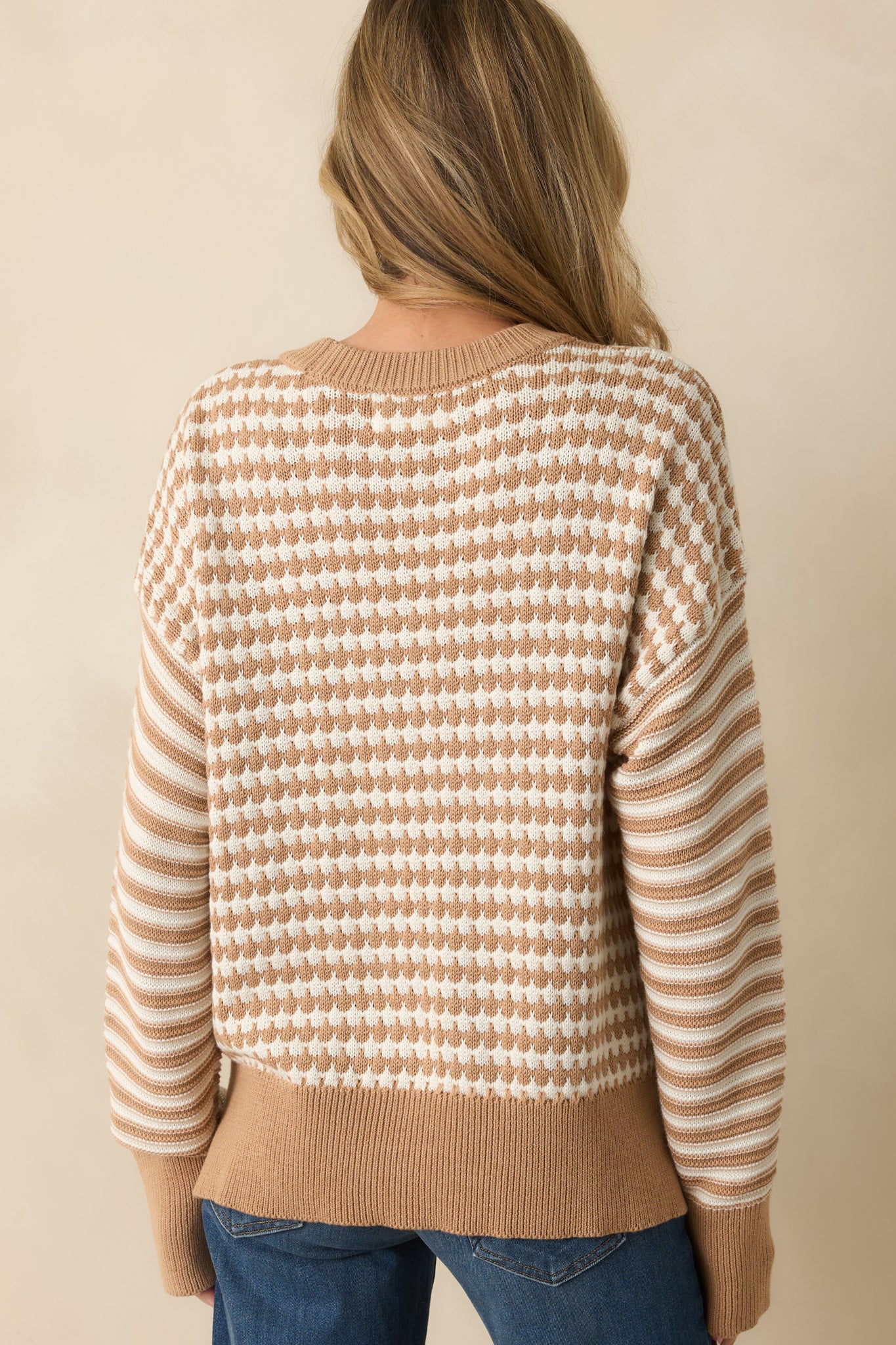 Rear view of the camel brown sweater showing long sleeves, striped detailing, and relaxed fit across the back