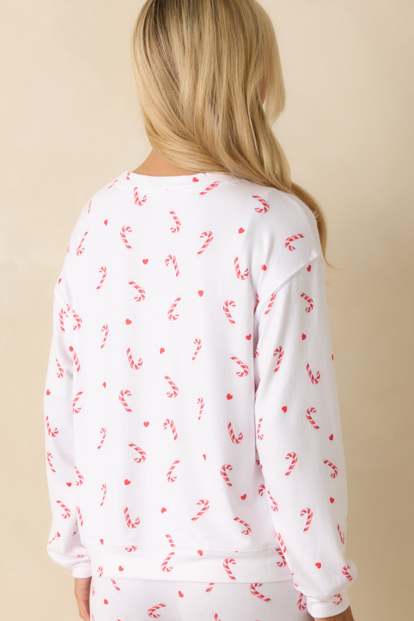 Rear view of the white knit top featuring an allover candy-cane print and relaxed silhouette.