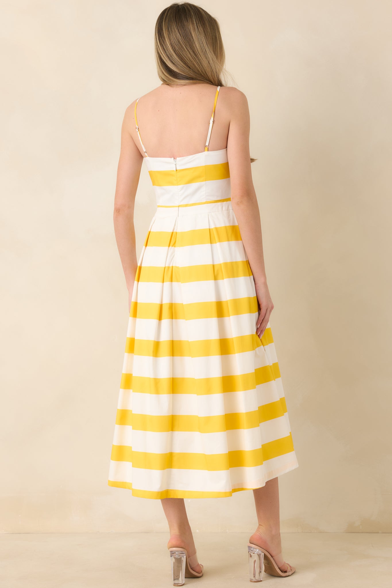 Rear view of the yellow and white striped midi dress with sleeveless silhouette and full skirt.