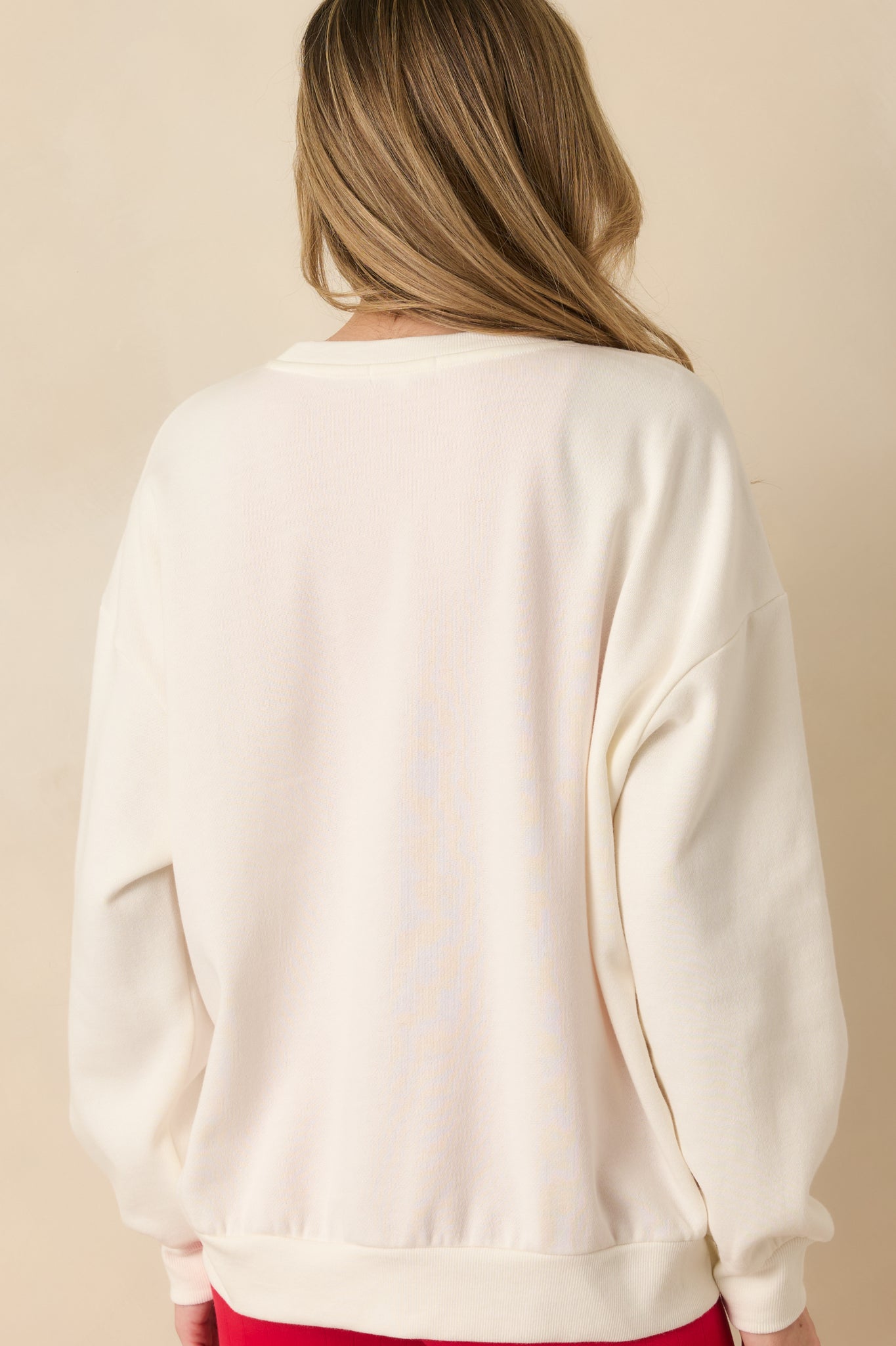 Rear view of the ivory sweatshirt showing the oversized silhouette and ribbed hem