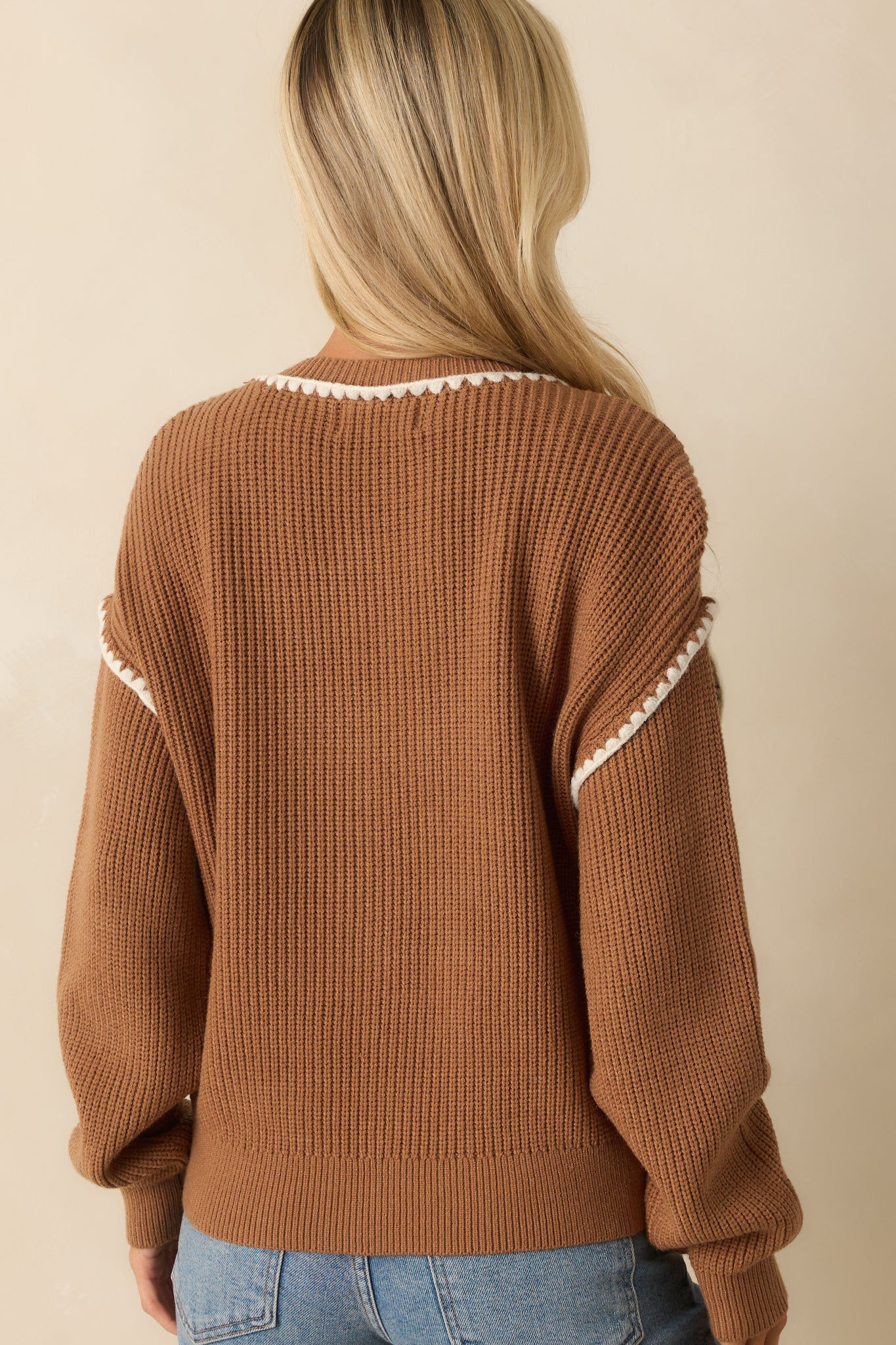 Rear view of the ribbed knit camel cardigan with long sleeves and subtle white trim along the edges.