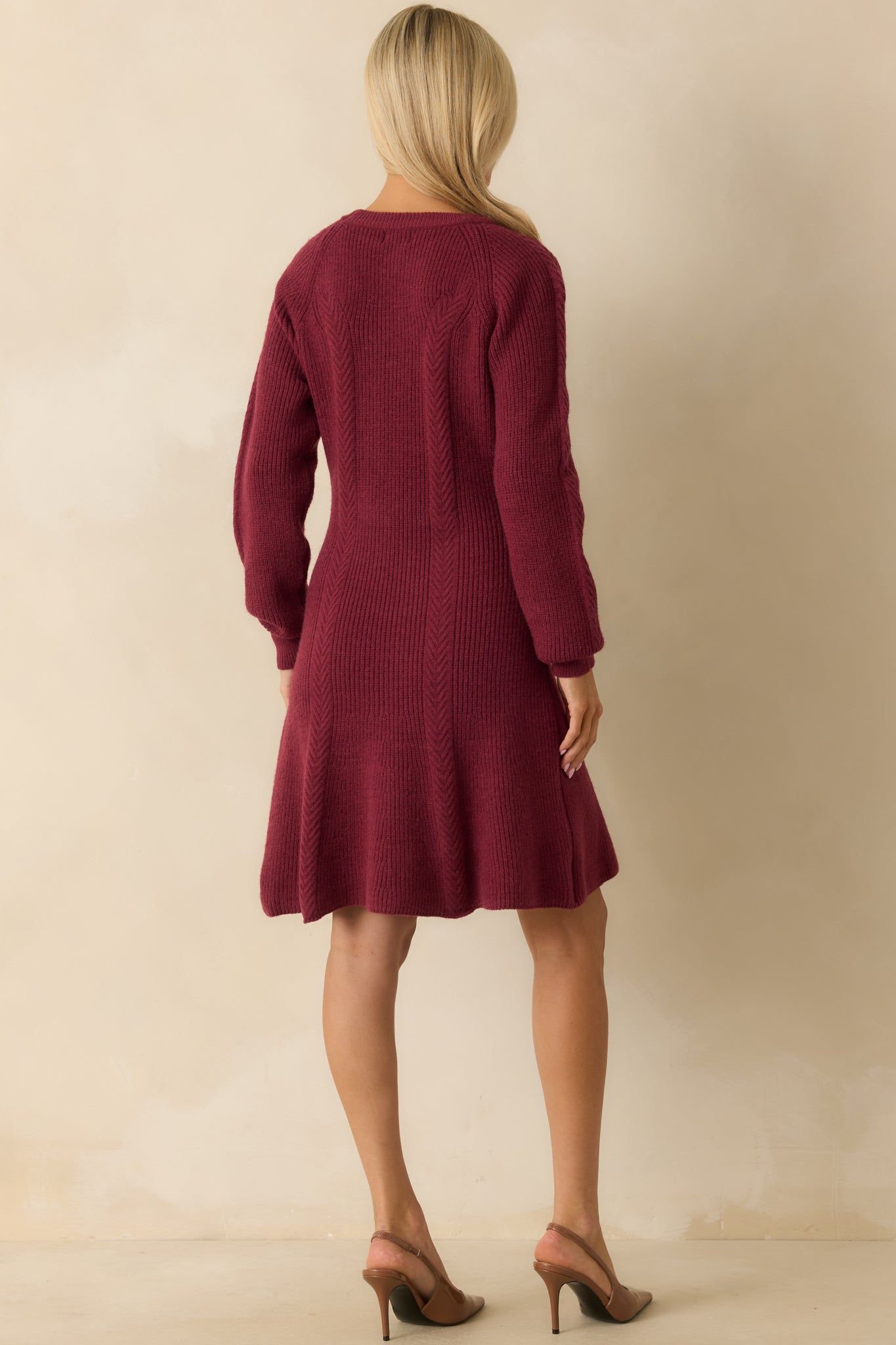 Rear view of the burgundy ribbed sweater dress highlighting the fitted bodice, ribbed cuffs, and flared hemline.