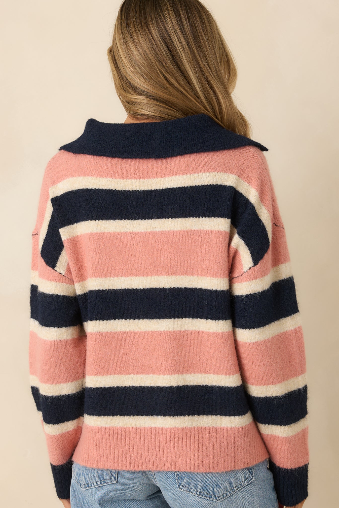 Rear view of the striped sweater displaying continuous horizontal striping, long sleeves, and ribbed hem.