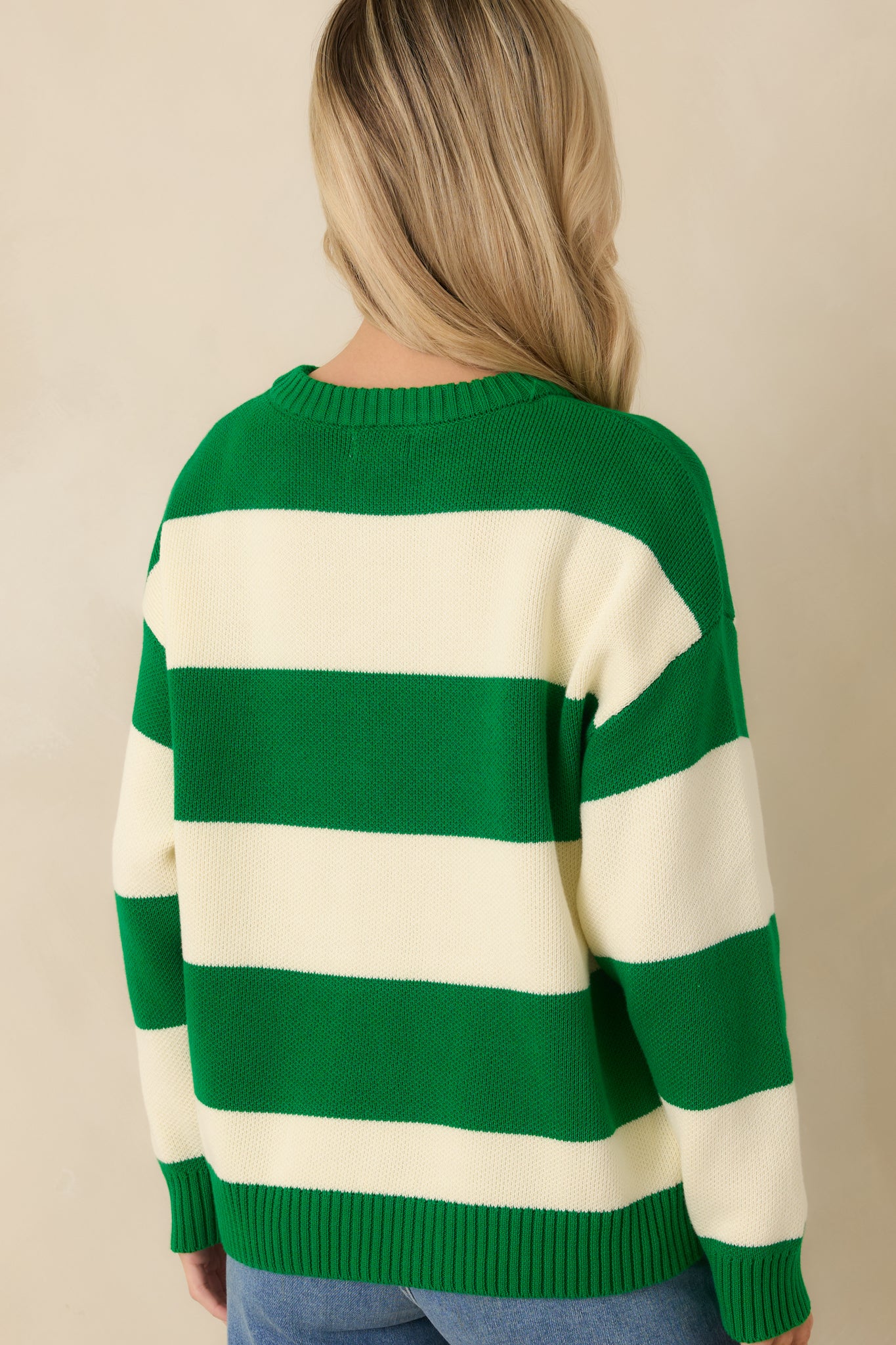 Rear view of the green and ivory striped knit sweater showing a relaxed fit and ribbed hemline.