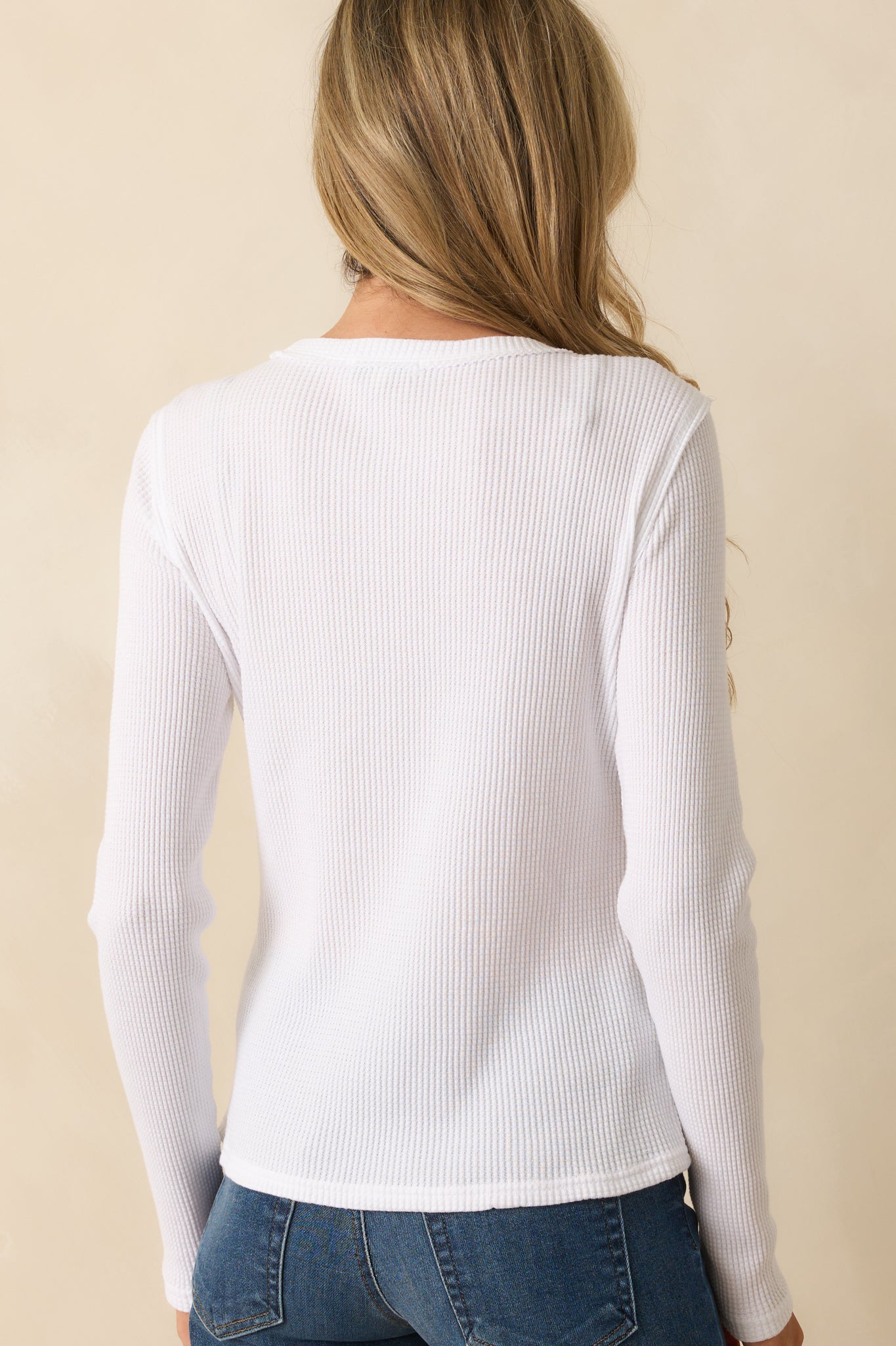 Rear view of the white thermal top showing the smooth knit back, long sleeves, and straight hem.