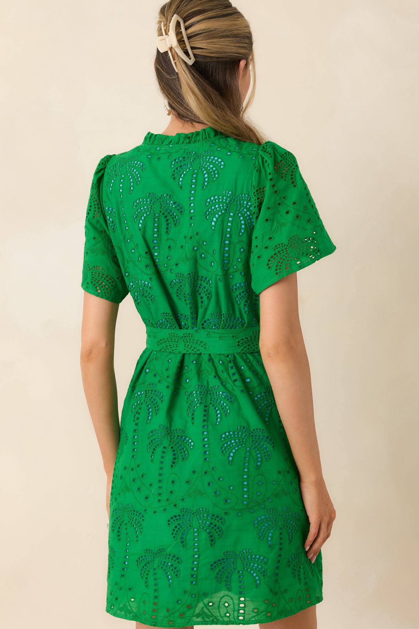 Rear view of white cotton eyelet mini dress with short sleeves and flowing fit.