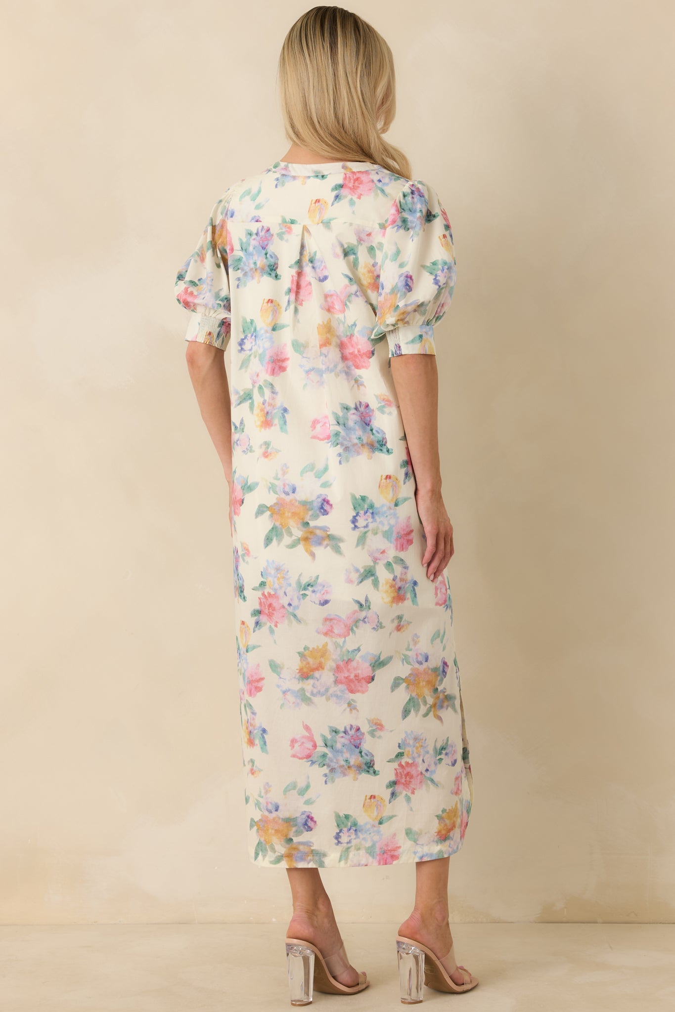Rear view of white floral maxi dress highlighting relaxed silhouette, short puff sleeves, and flowing maxi-length hem.