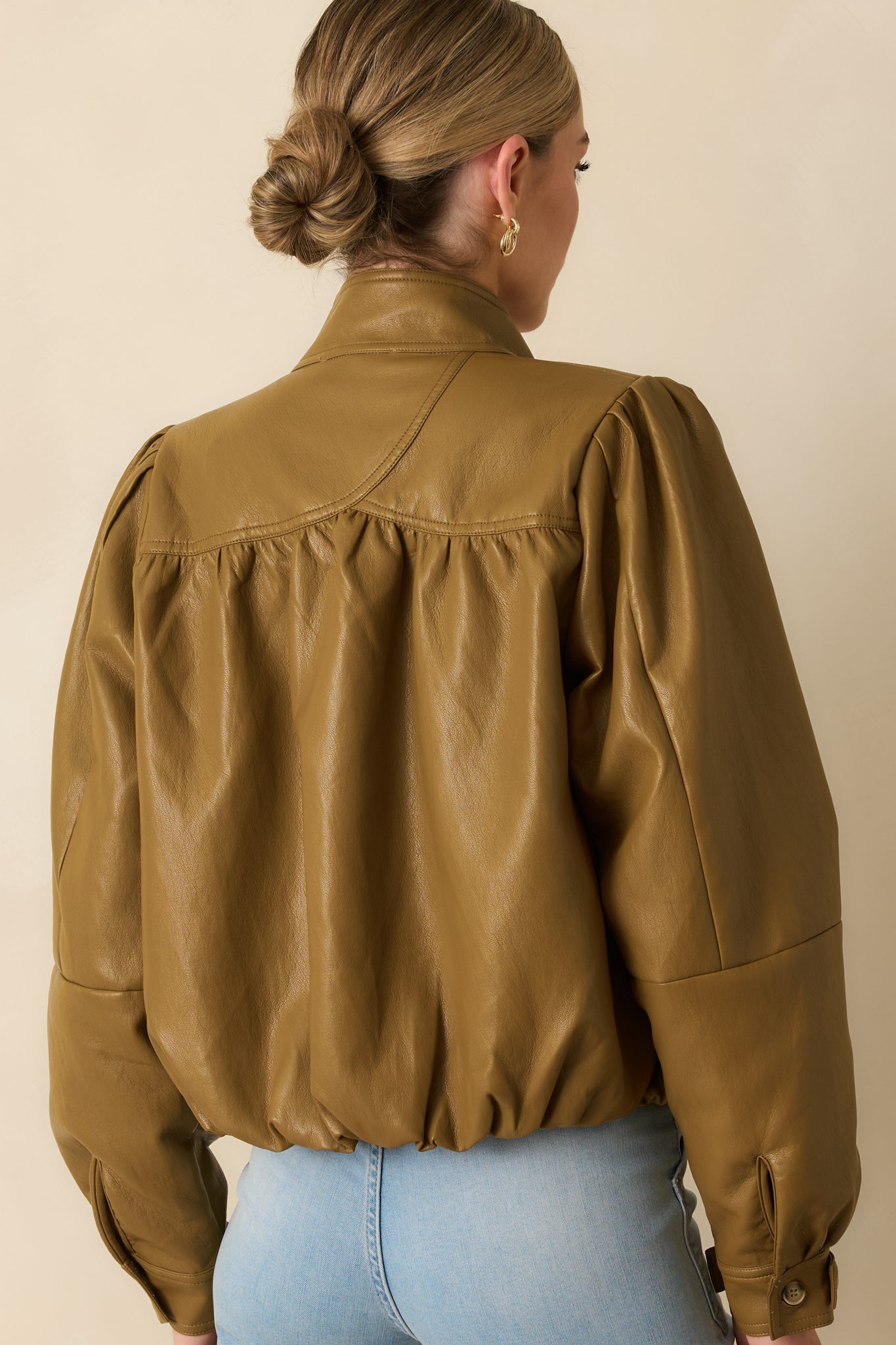 Rear view of the olive brown faux leather jacket highlighting the smooth paneling and softly structured fit.