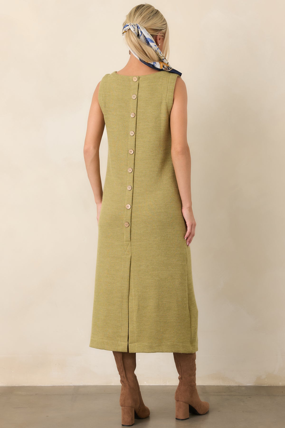 Rear view of the olive green rib knit midi dress showing the decorative button detail and back slit hem.