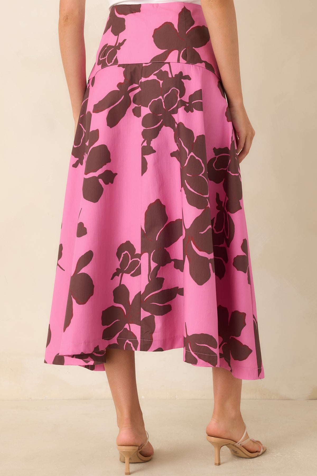 Rear view of the pink cotton midi skirt featuring the oversized chocolate brown floral print, wide waistband, full A-line shape, and concealed side zipper.