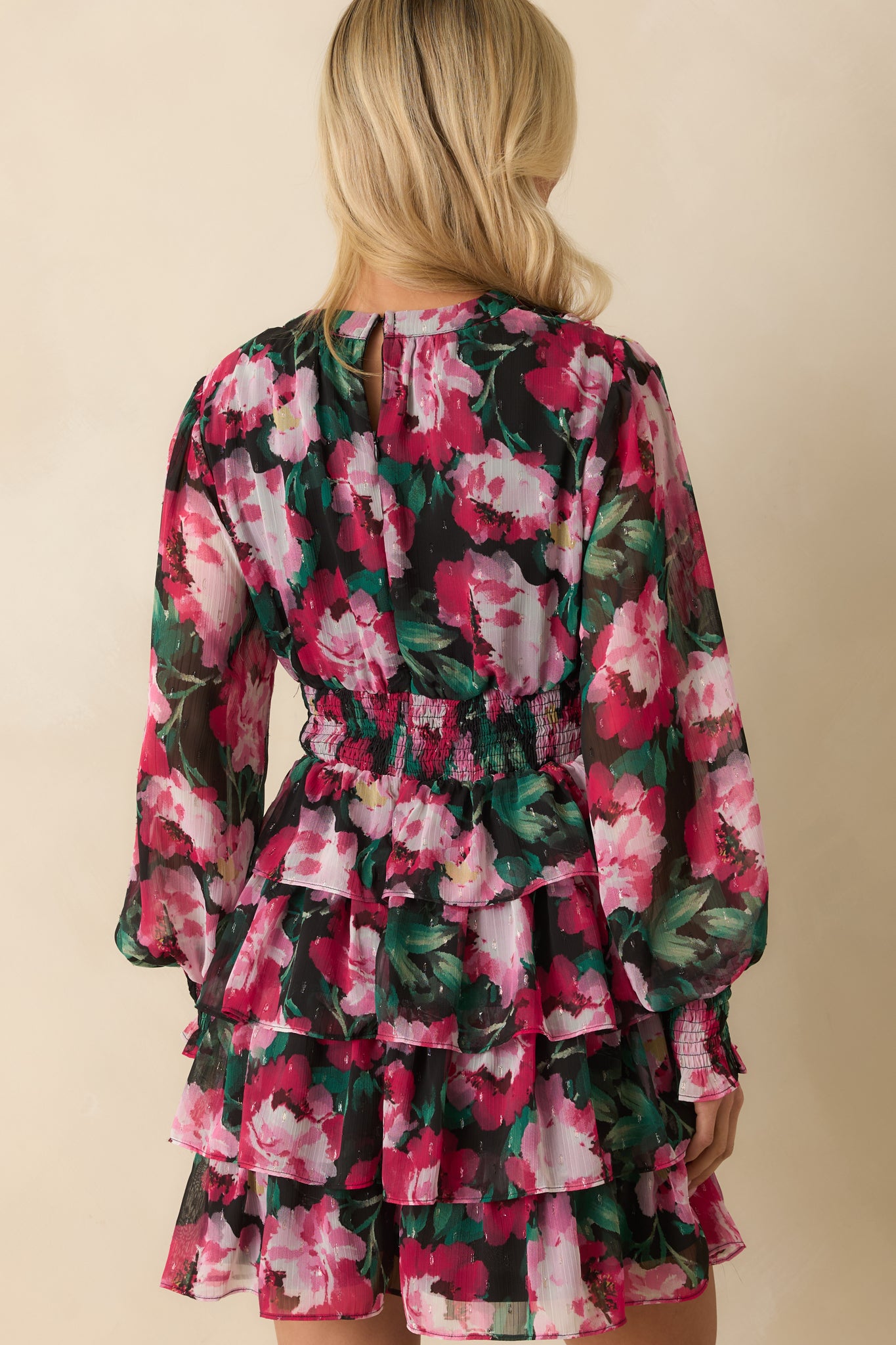Rear view of the pink floral mini dress showing the tiered ruffle skirt, long sleeves, and continuous floral pattern.