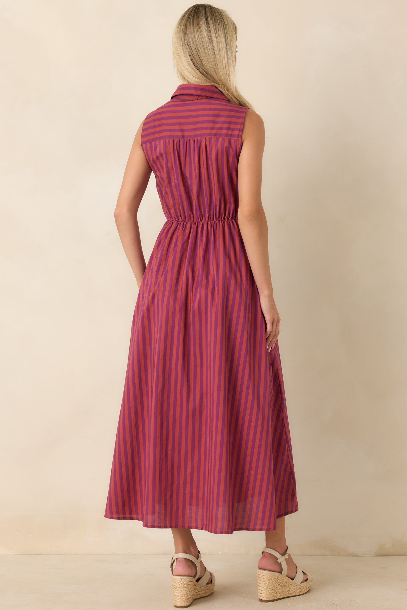 Rear view of the plum and burgundy striped midi dress highlighting the elasticized waist, sleeveless cut, and flowing A-line skirt.