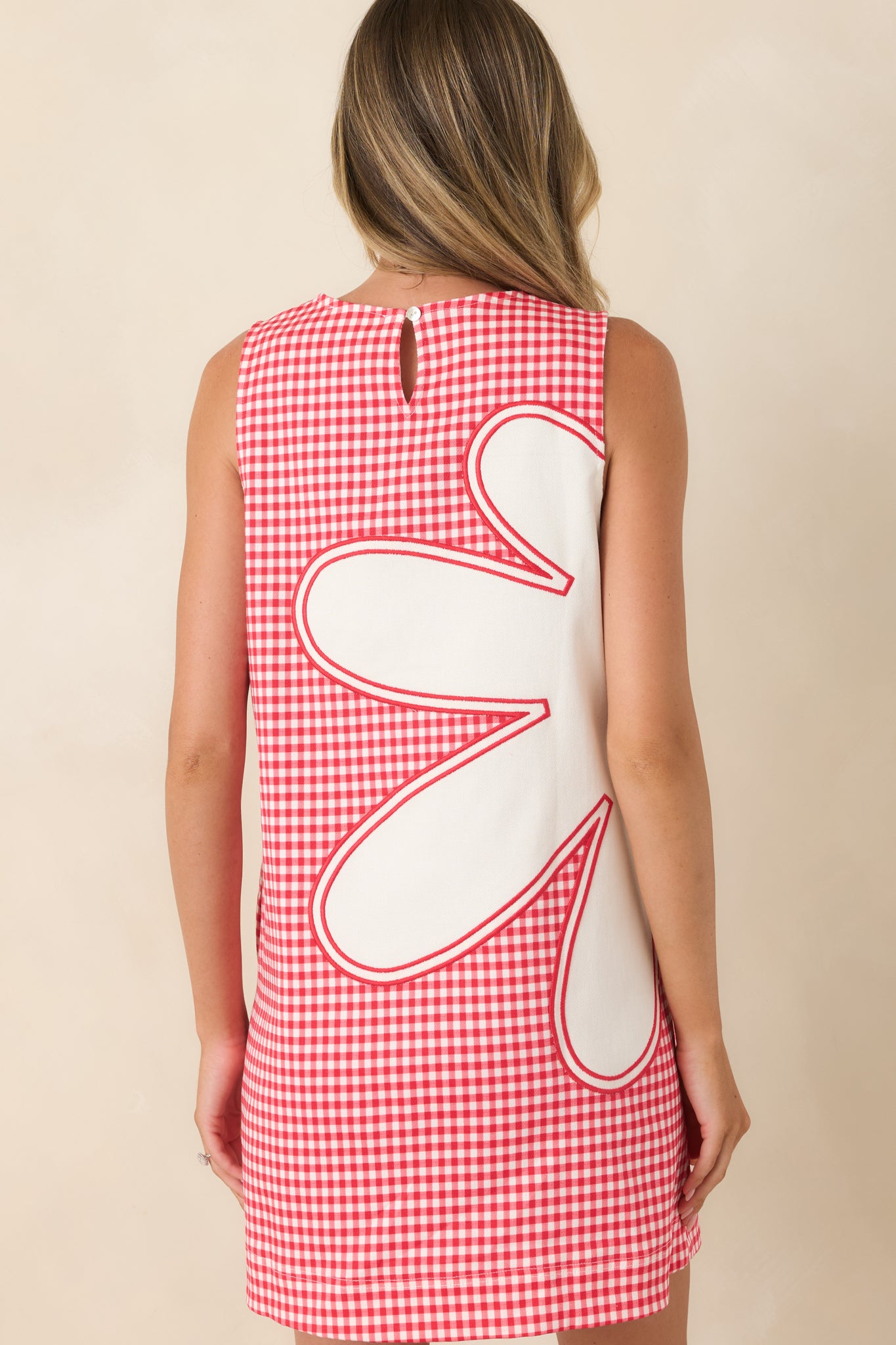 Rear view of the red gingham mini dress highlighting the sleeveless shift silhouette and back keyhole button closure.