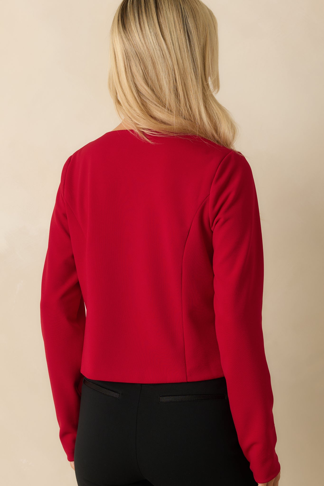 Rear view of the red jacket, showing its tailored cropped silhouette and smooth woven finish.