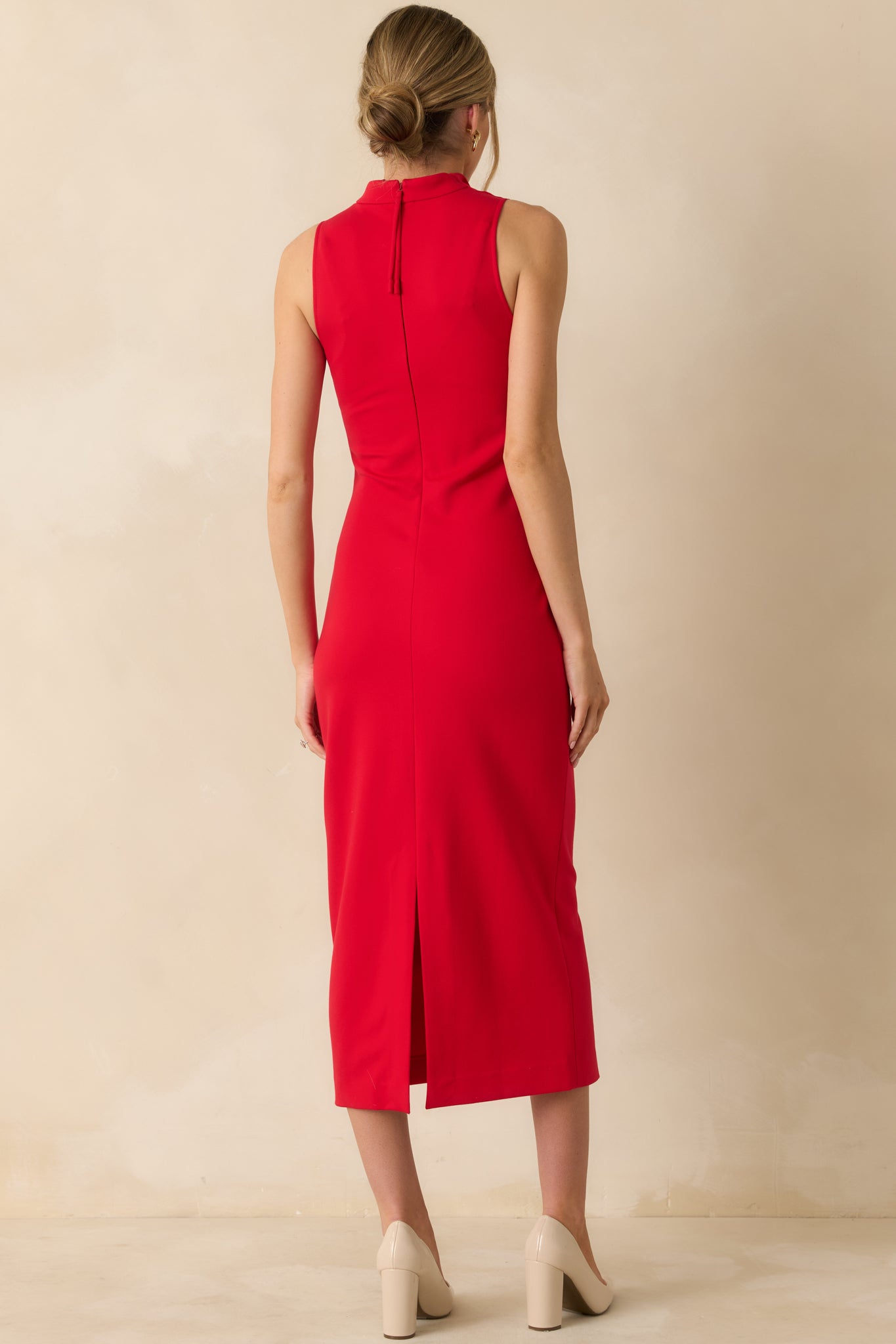 Rear view of the red sleeveless midi dress highlighting the back slit for ease of movement and its fitted, figure-flattering design.