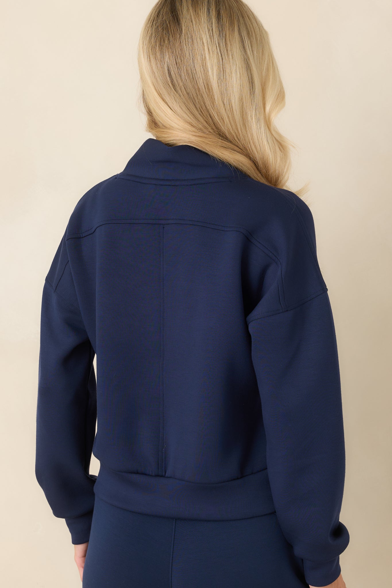Rear view of the pullover showcasing the relaxed silhouette, dropped shoulders, long sleeves, and wide hem detail.