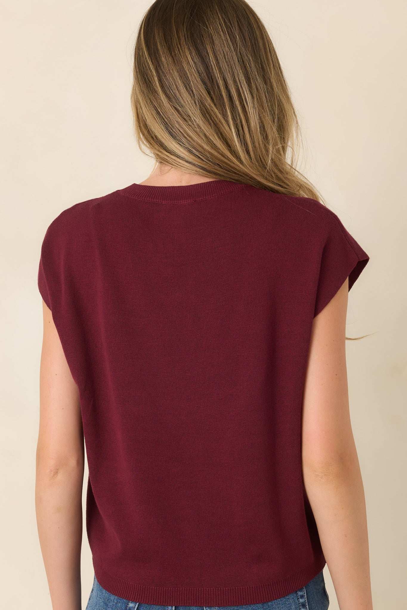 Rear view of the lightweight knit sweater featuring its straight silhouette, short relaxed sleeves, crew neckline, and ribbed hem.