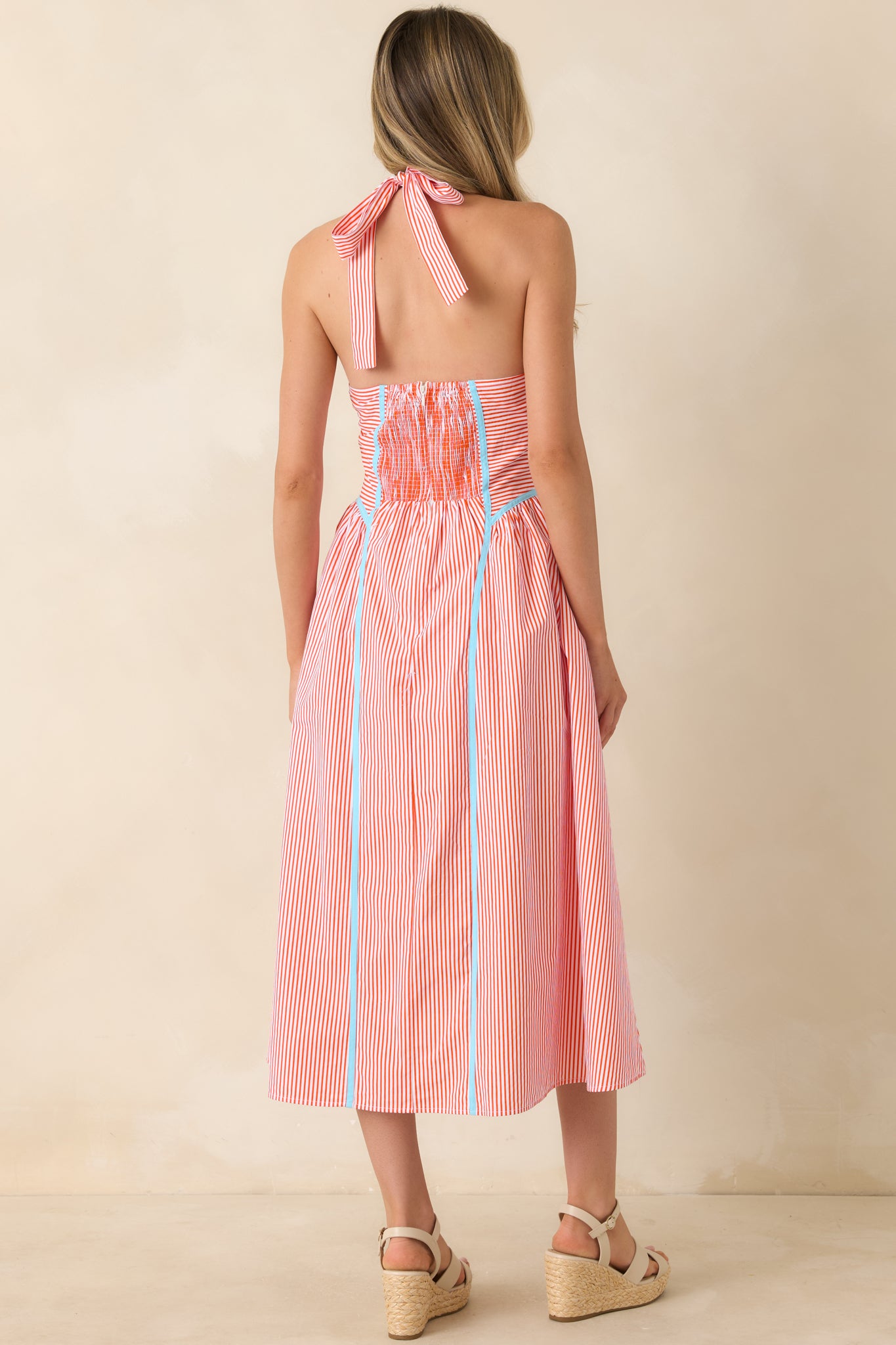 Rear view of the midi dress showcasing the smocked back panel, halter design, and flowing skirt silhouette.
