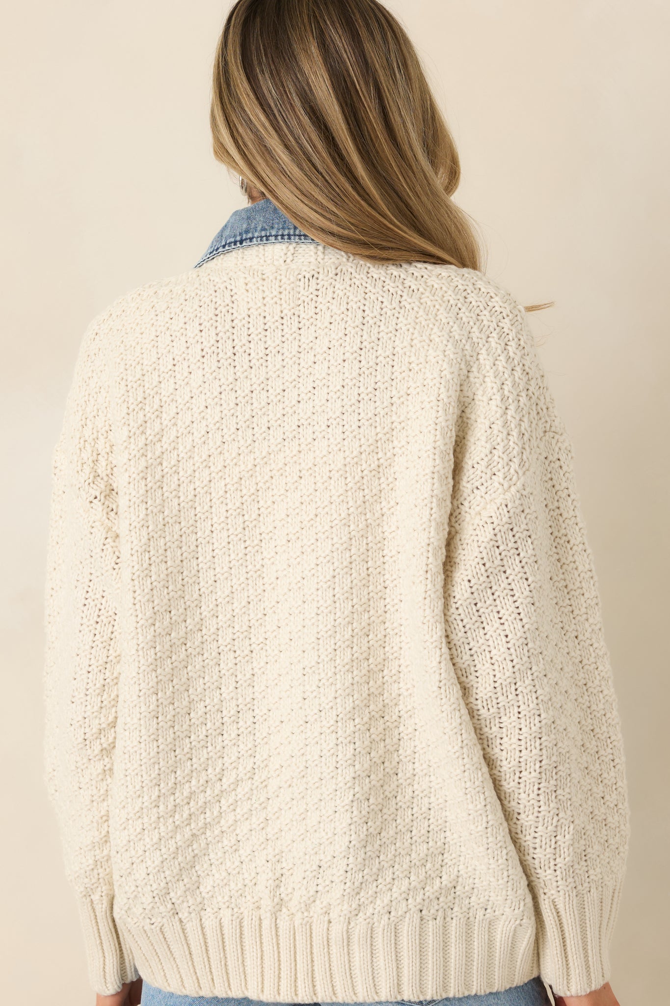 Rear view of the ivory knit jacket showcasing the textured body and clean silhouette with denim collar detail.