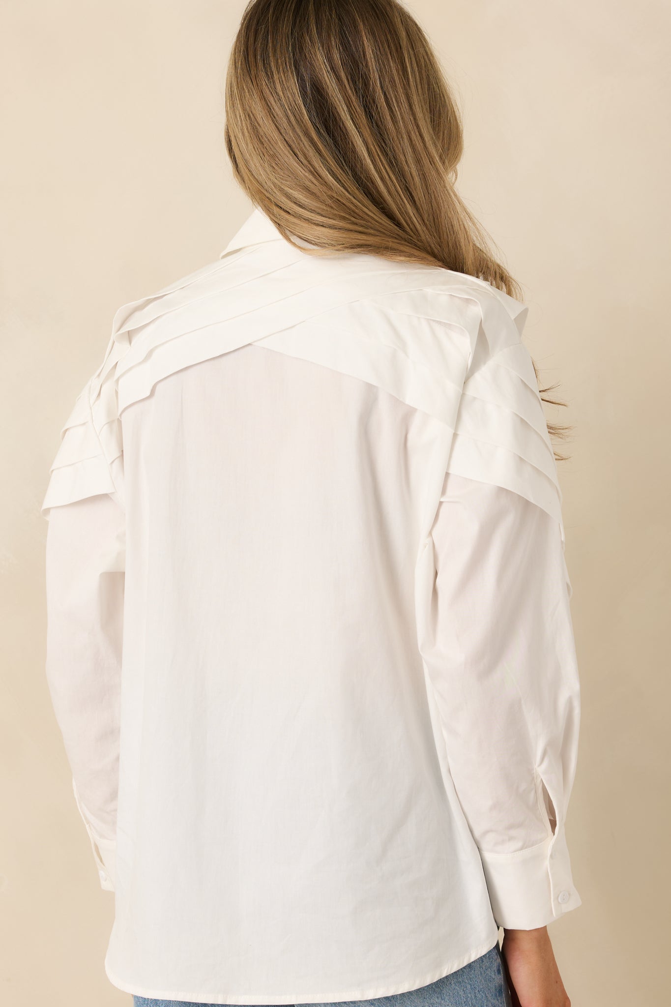 Rear view of a white cotton button-up blouse showing a smooth woven finish and clean construction.