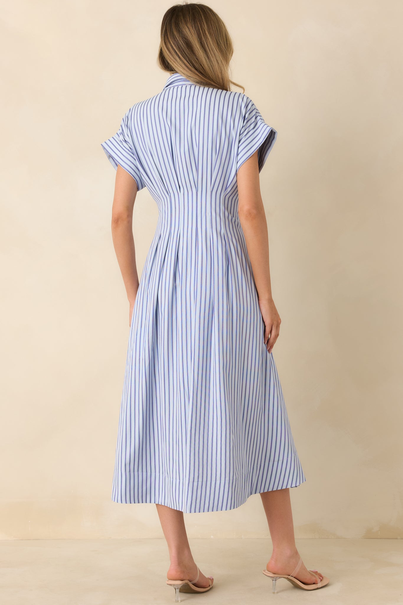 Rear of the blue midi dress showing continuous vertical dark and light blue stripes, clean back panel lines, and pocket seam placement.