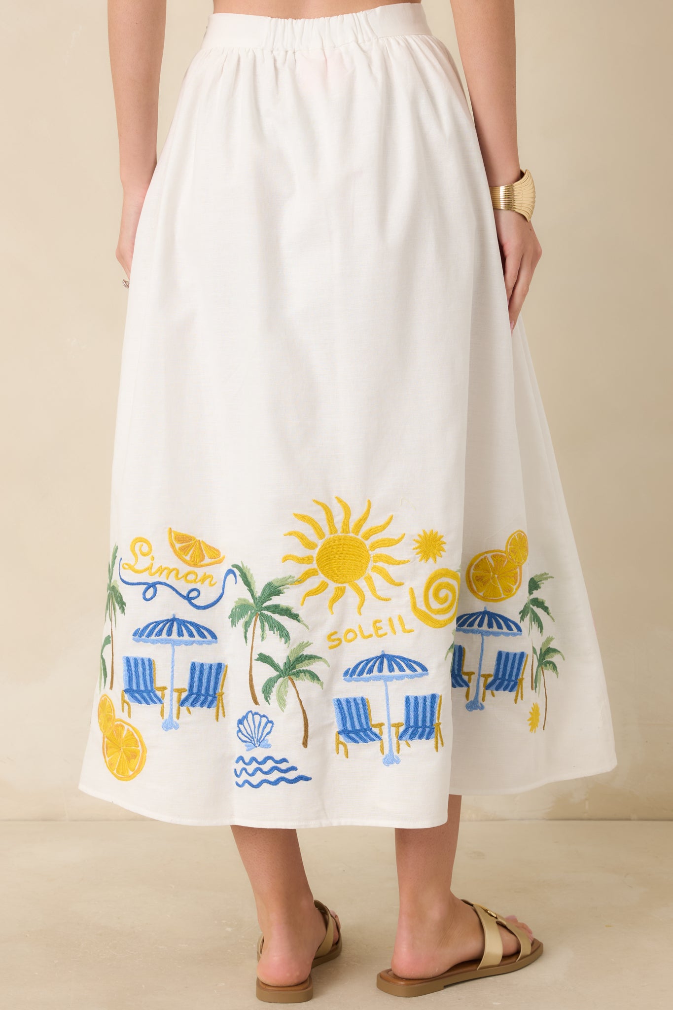 Rear view of the midi skirt showing the full, flowing silhouette, elastic waistband, and embroidered hem detailing continuing across the back for a complete, standout finish.