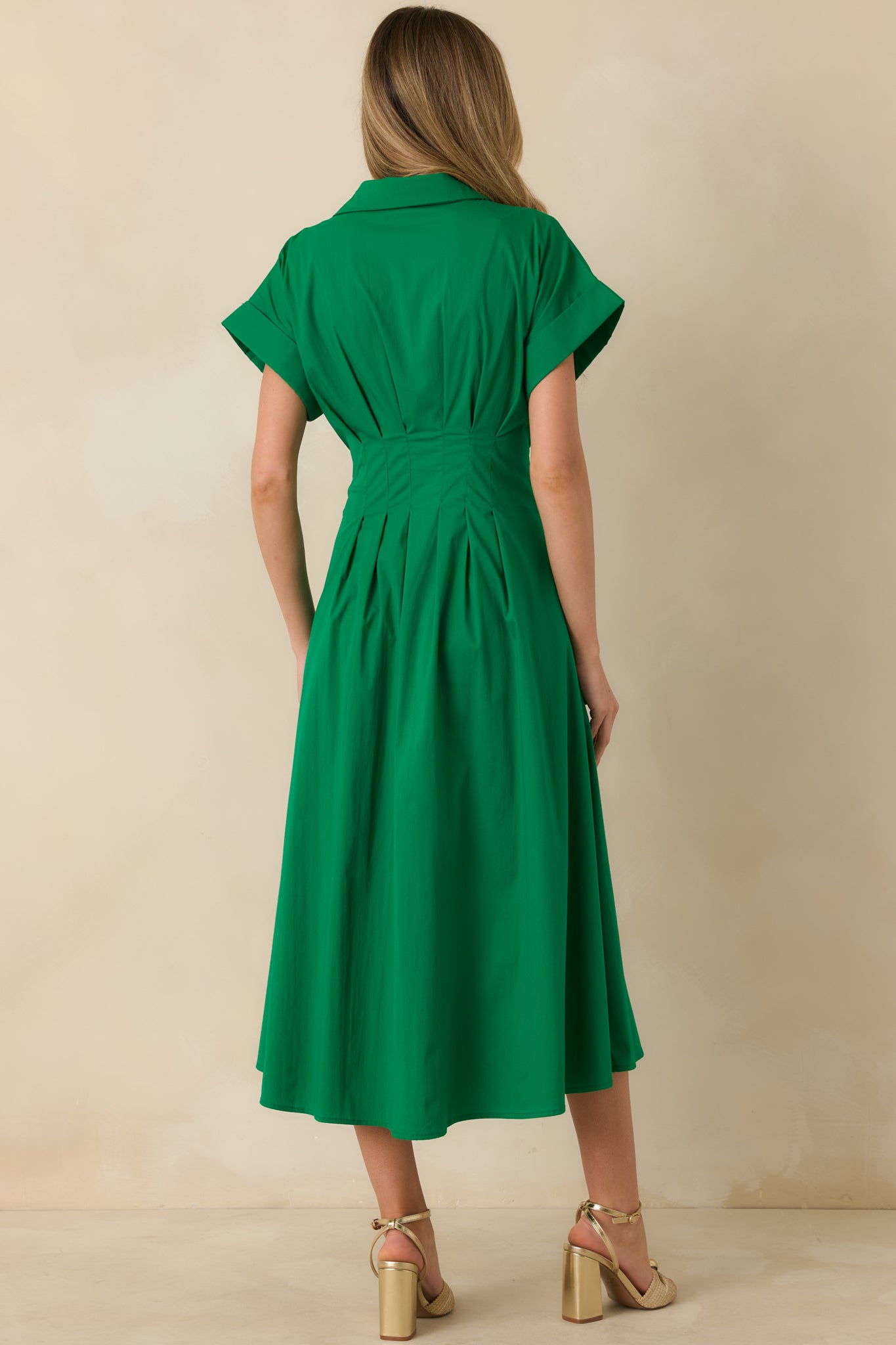 Rear view of the green midi dress showing the smooth back panel, short sleeves, and flowing midi-length skirt.