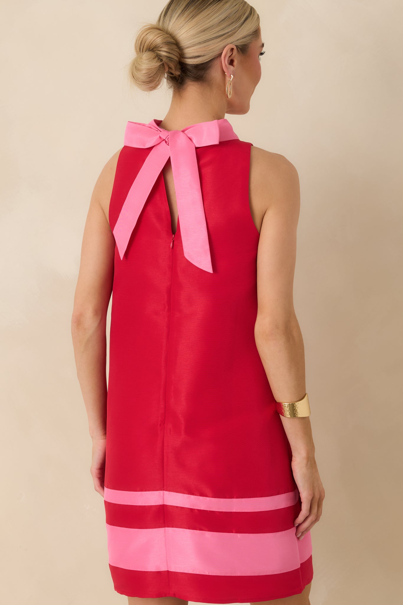 Rear view of the red mini dress showing the statement bow at the back neckline and hidden zipper with keyhole opening.