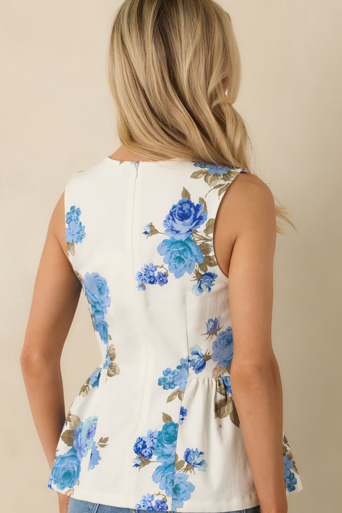 Rear view of the blue floral peplum top showing the zipper closure, fitted waist, and flared hem.