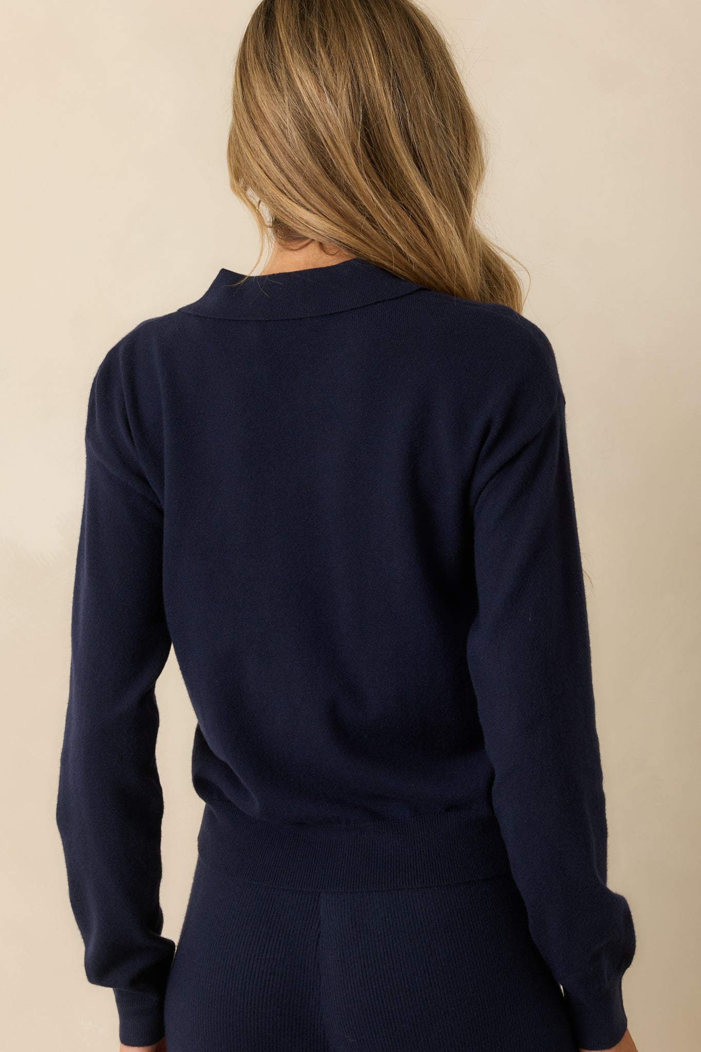 Rear view of the sweater displaying the smooth knit back and long sleeves.