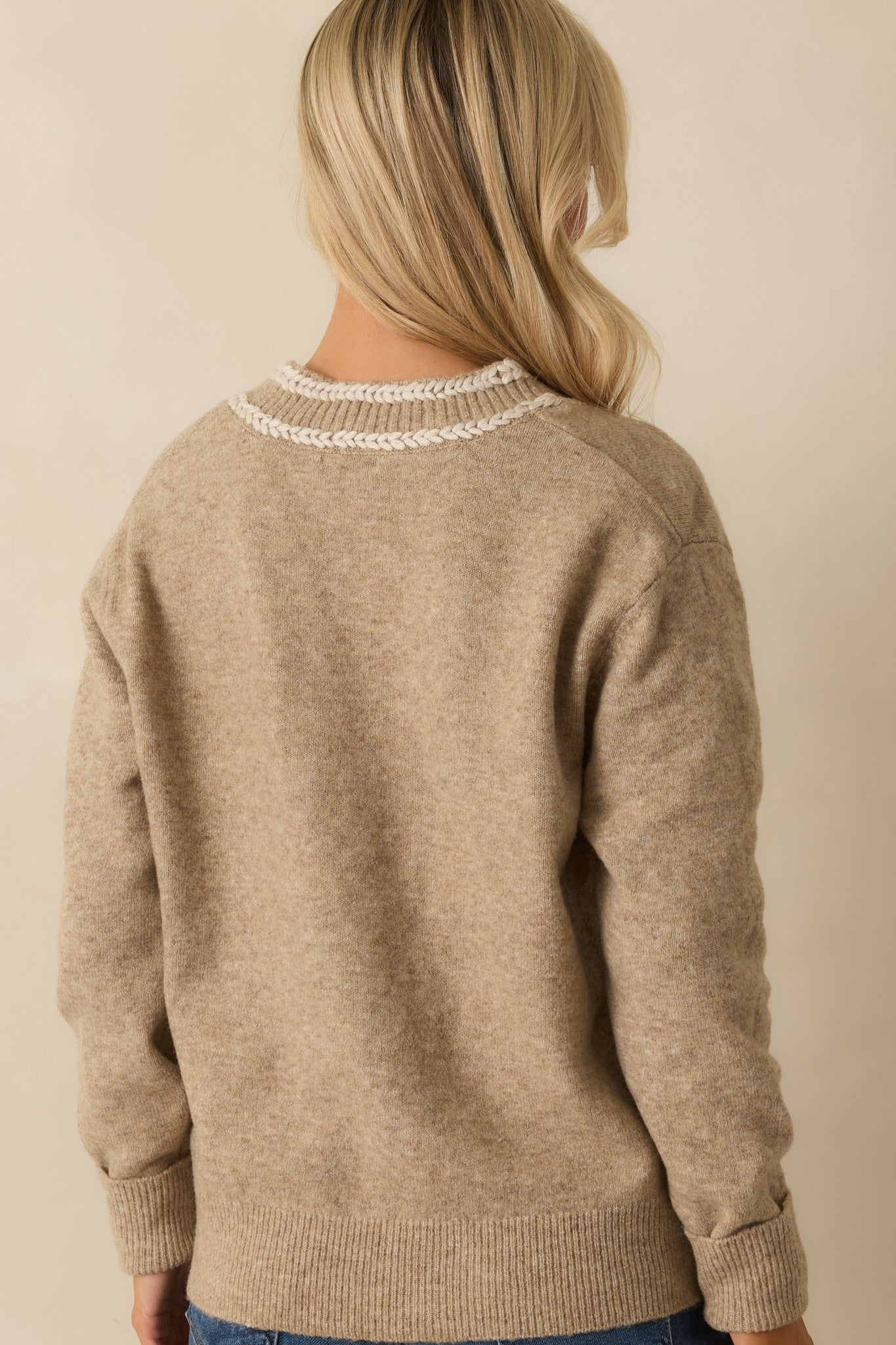 Rear view of the tan sweater showing long sleeves and relaxed fit.
