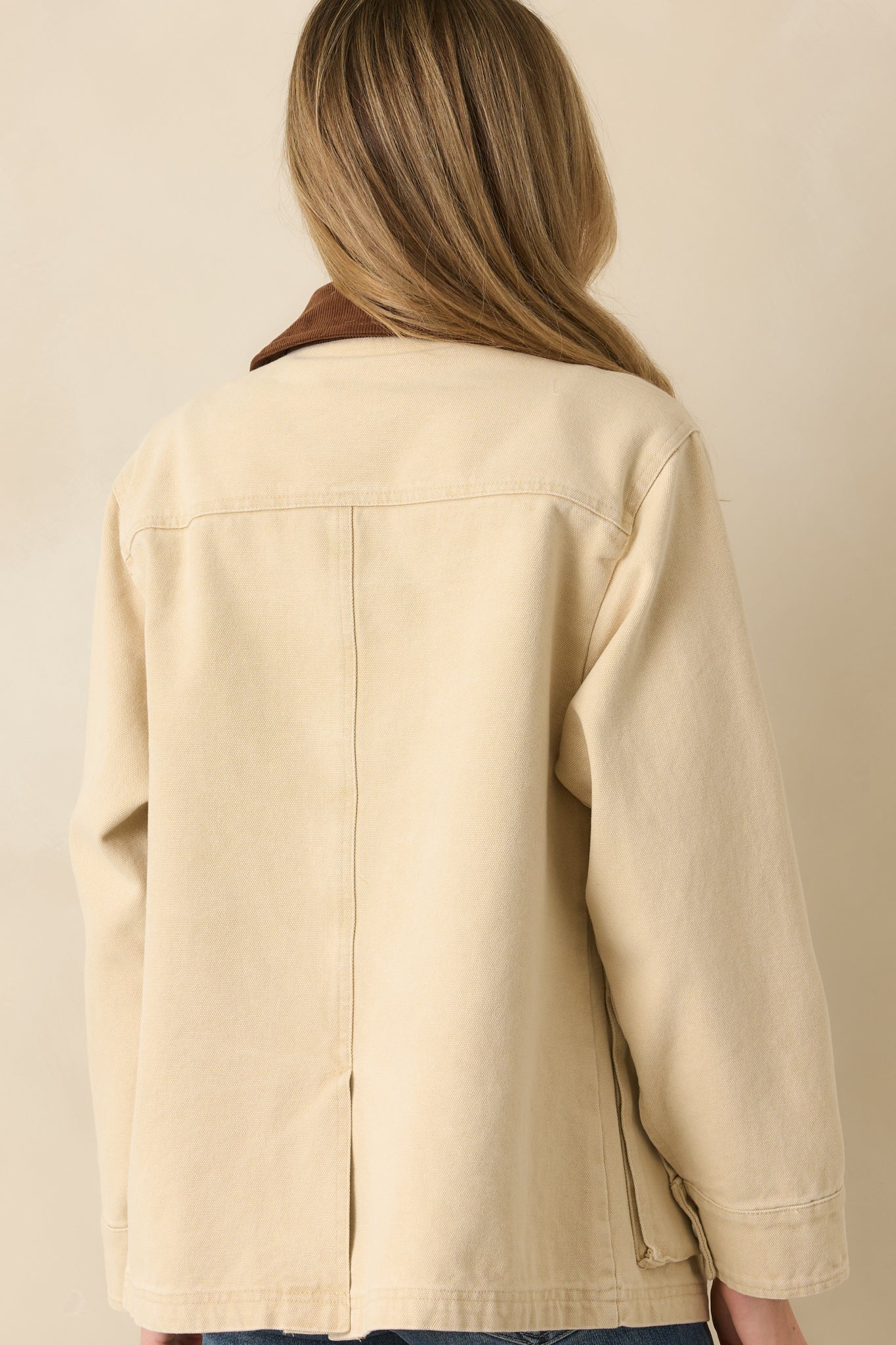 Rear view of the taupe canvas jacket showing its straight silhouette and clean seams.