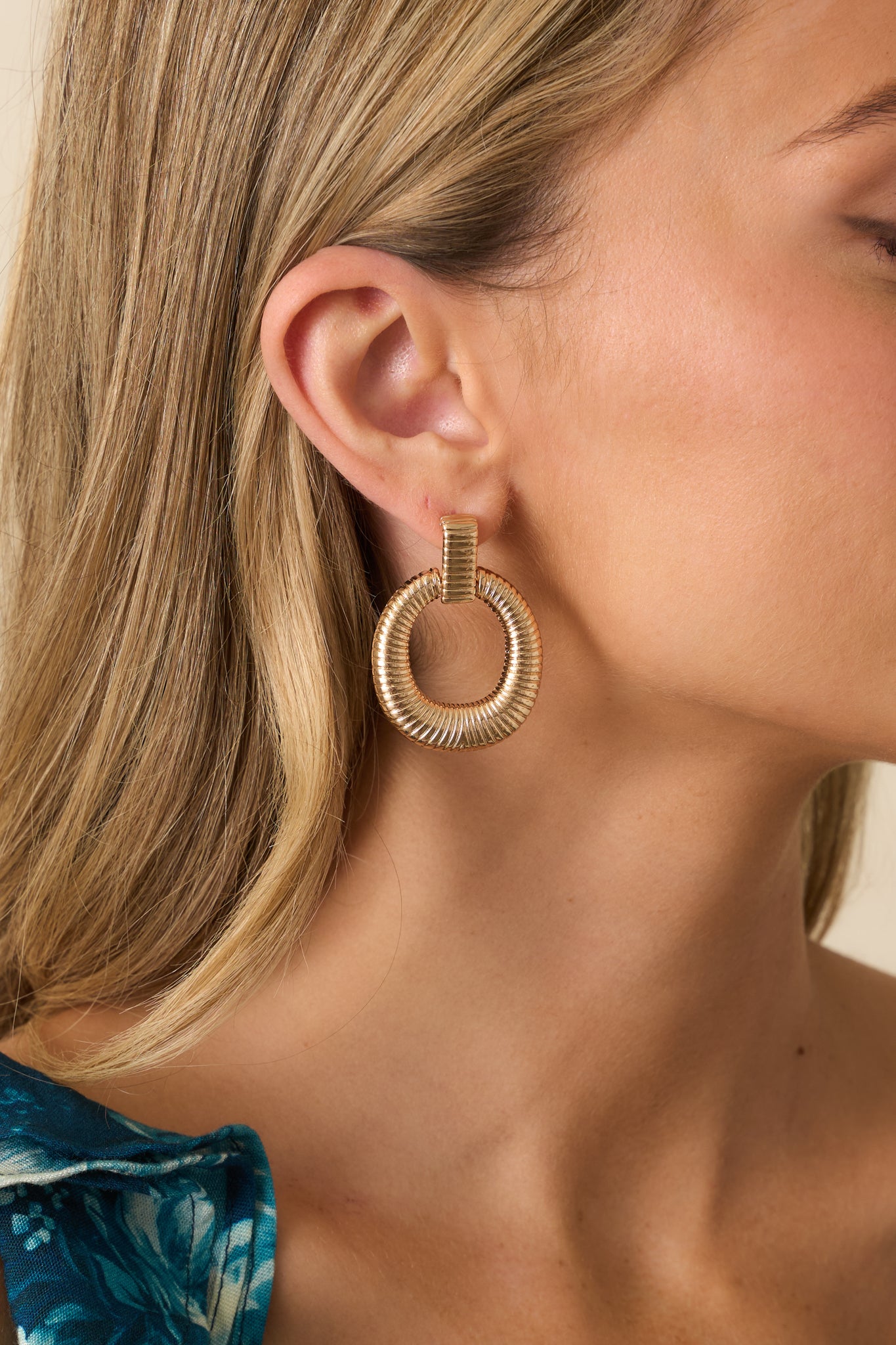 Detail of the earrings showing the rectangular stud and attached ribbed hoop design.