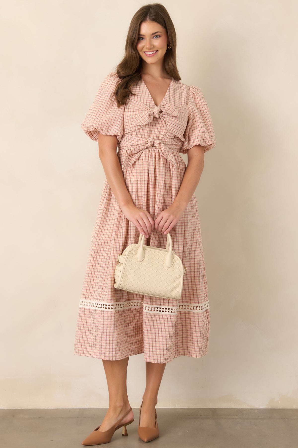 Red and beige plaid midi dress with a fitted bodice, puff sleeves, elasticized waist, oversized front ties, and softly voluminous skirt.
