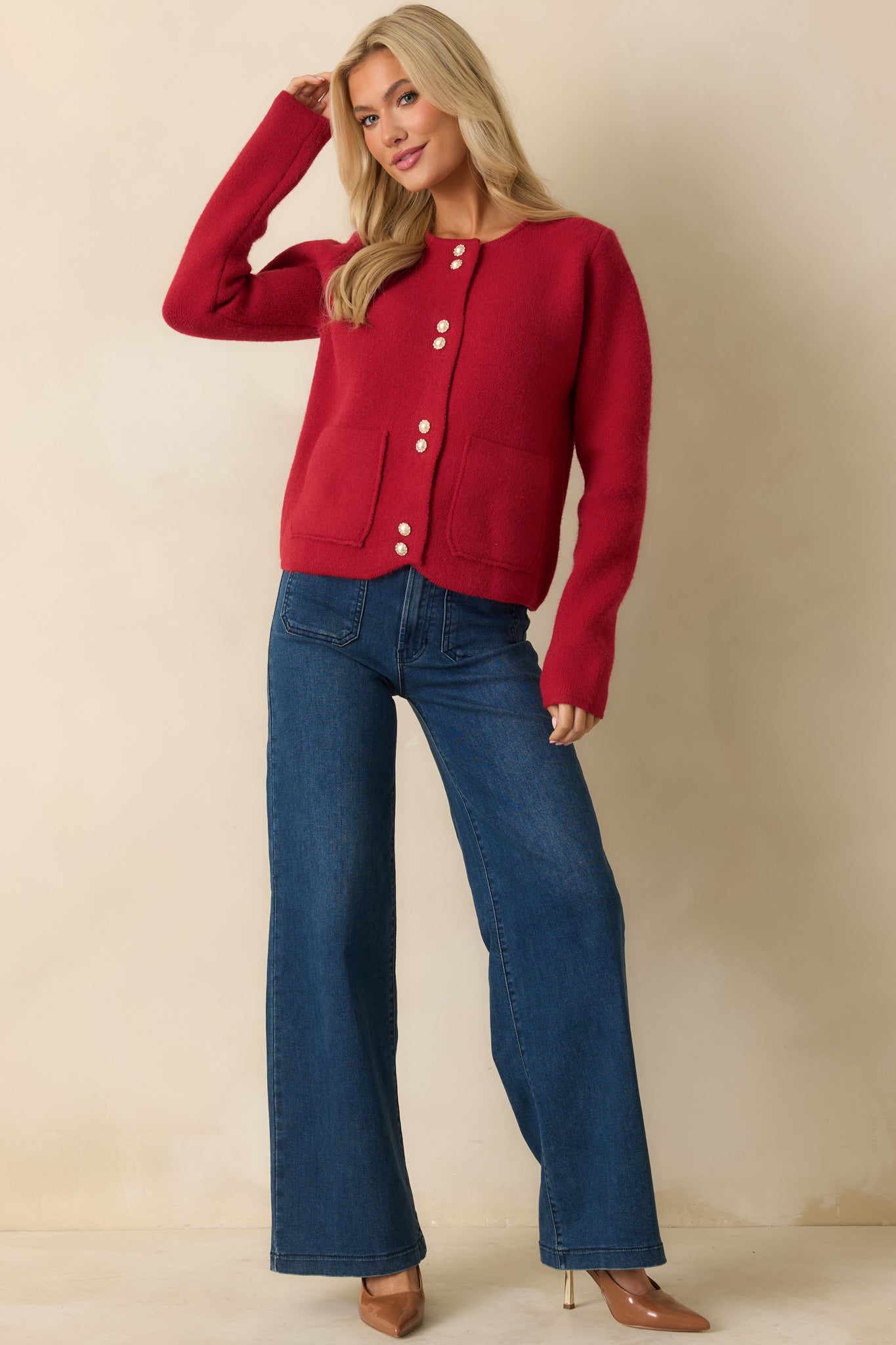Soft medium-weight red cardigan featuring long sleeves, a classic round neckline, and pearl-accented buttons down the front.